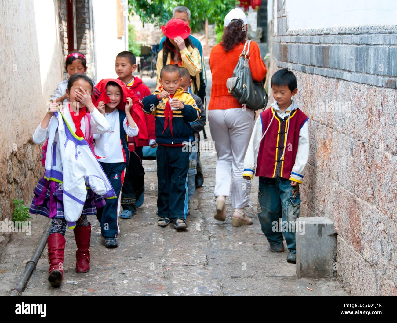China: Schulkinder in einer Hinterstraße der Altstadt von Lijiang, Provinz Yunnan. Die Naxi oder Nakhi sind eine ethnische Gruppe, die in den Ausläufern des Himalaya im Nordwesten der Provinz Yunnan und im Südwesten der Provinz Sichuan in China lebt. Man geht davon aus, dass die Naxi ursprünglich aus Tibet stammen und bis vor kurzem die Landhandelsverbindungen mit Lhasa und Indien aufrechterhalten haben. Die Naxi gehören zu den 56 ethnischen Gruppen, die von der Volksrepublik China offiziell anerkannt wurden. Die Naxi sind traditionell Anhänger der Dongba-Religion. Stockfoto