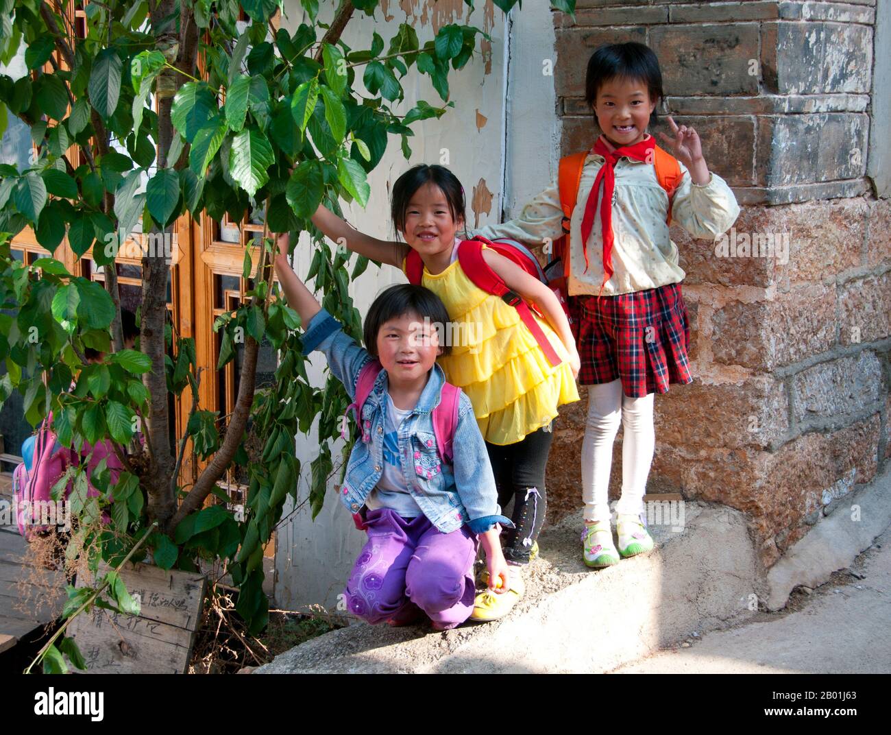 China: Schulmädchen in der Altstadt auf dem Heimweg, Altstadt von Lijiang, Provinz Yunnan. Die Naxi oder Nakhi sind eine ethnische Gruppe, die in den Ausläufern des Himalaya im Nordwesten der Provinz Yunnan und im Südwesten der Provinz Sichuan in China lebt. Man geht davon aus, dass die Naxi ursprünglich aus Tibet stammen und bis vor kurzem die Landhandelsverbindungen mit Lhasa und Indien aufrechterhalten haben. Die Naxi gehören zu den 56 ethnischen Gruppen, die von der Volksrepublik China offiziell anerkannt wurden. Die Naxi sind traditionell Anhänger der Dongba-Religion. Stockfoto