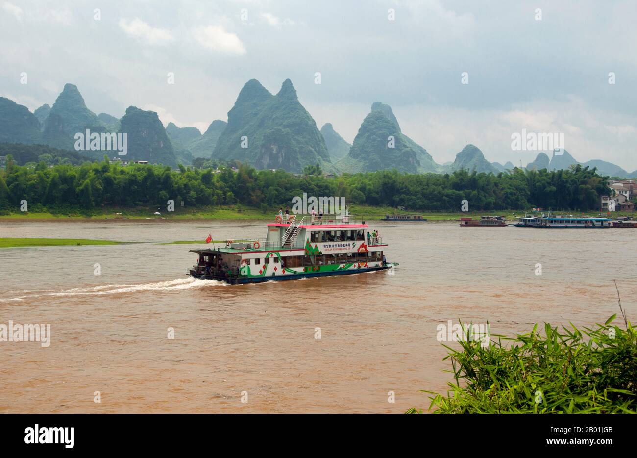 China: Boote auf dem Li-Fluss in Yangshuo, nahe Guilin, Provinz Guangxi. Yangshuo ist zu Recht berühmt für seine dramatische Landschaft. Es liegt am Westufer des Flusses Li (Lijiang) und ist nur 60 km stromabwärts von Guilin. In den letzten Jahren ist es zu einem beliebten Reiseziel bei Touristen geworden und hat gleichzeitig das Gefühl einer kleinen Flussstadt bewahrt. Guilin ist der Schauplatz von Chinas berühmtesten Landschaften und inspiriert Tausende von Gemälden über viele Jahrhunderte. Die „schönsten Berge und Flüsse unter dem Himmel“ sind so inspirierend, dass Dichter, Künstler und Touristen dieses Chinas wichtigste natürliche Attraktion gemacht haben. Stockfoto