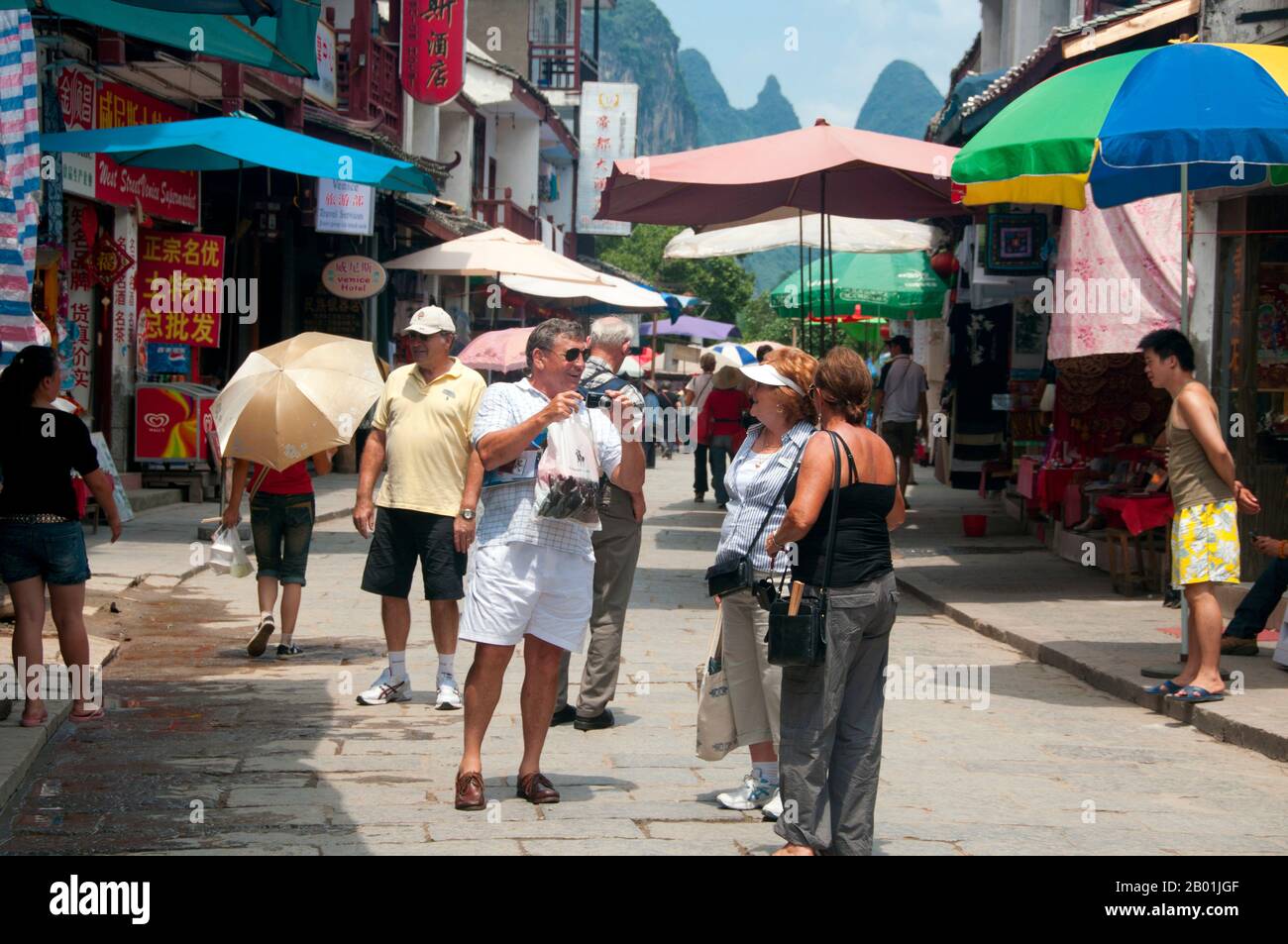 China: Touristen in Xi Jie („Foreigner Street“), Yangshuo, nahe Guilin, Provinz Guangxi. Yangshuo ist zu Recht berühmt für seine dramatische Landschaft. Es liegt am Westufer des Flusses Li (Lijiang) und ist nur 60 Kilometer stromabwärts von Guilin. In den letzten Jahren ist es zu einem beliebten Reiseziel bei Touristen geworden und hat gleichzeitig das Gefühl einer kleinen Flussstadt bewahrt. Guilin ist der Schauplatz von Chinas berühmtesten Landschaften und inspiriert Tausende von Gemälden über viele Jahrhunderte. Sie wurden oft als die „schönsten Berge und Flüsse unter dem Himmel“ bezeichnet. Stockfoto