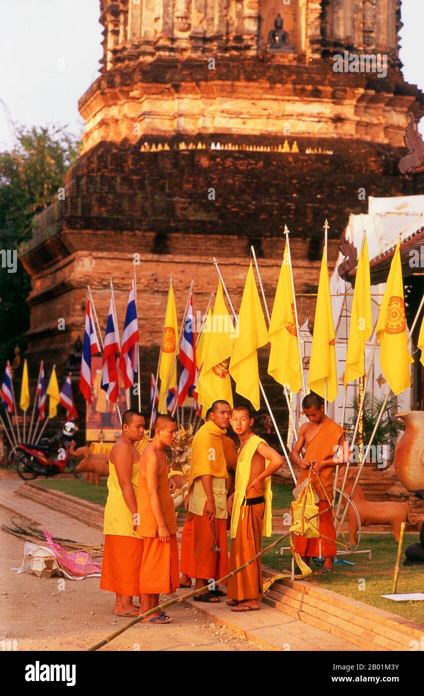 Thailand: Mönche, die Flaggen für ein bevorstehendes Festival vor den Chedi des 16. Jahrhunderts im Wat Lok Moli, Chiang Mai, Nordthailand ausrollen. Wat Lok Moli oder „Topknot der Welt“ wurde vermutlich von König Ku Na, dem 6. König der Mangrai-Dynastie (1263–1578), gegründet, der zwischen 1367 und 1388 das Königreich Lan Na von Chiang Mai aus regierte. Es war wahrscheinlich ein königlicher Tempel, da die Nordseite der Stadt zu dieser Zeit ein königliches Viertel war; sicherlich genoss das Heiligtum eine lange und enge Verbindung mit den Mangrai-Herrschern. Stockfoto
