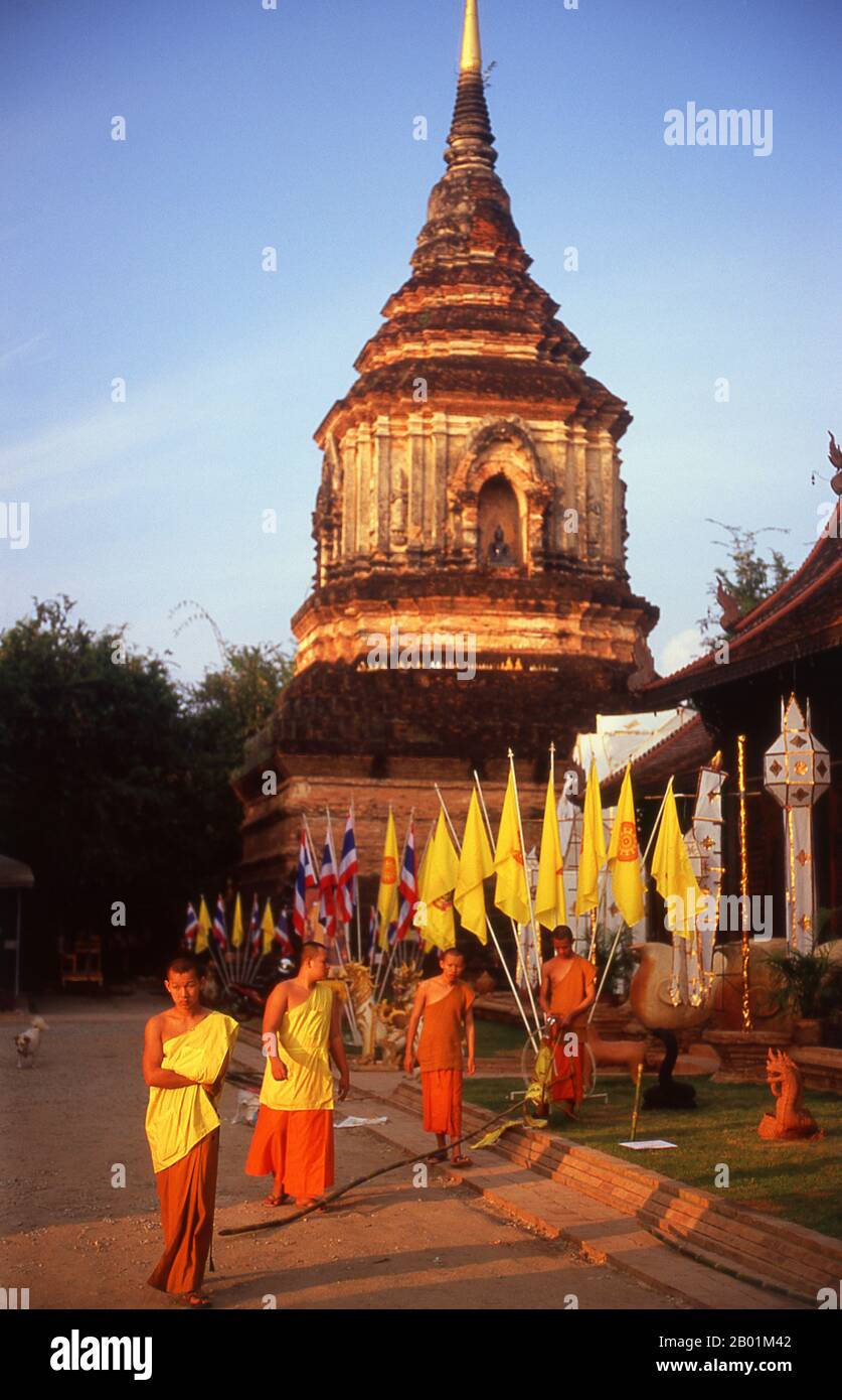 Thailand: Mönche, die Flaggen für ein bevorstehendes Festival vor den Chedi des 16. Jahrhunderts im Wat Lok Moli, Chiang Mai, Nordthailand ausrollen. Wat Lok Moli oder „Topknot der Welt“ wurde vermutlich von König Ku Na, dem 6. König der Mangrai-Dynastie (1263–1578), gegründet, der zwischen 1367 und 1388 das Königreich Lan Na von Chiang Mai aus regierte. Es war wahrscheinlich ein königlicher Tempel, da die Nordseite der Stadt zu dieser Zeit ein königliches Viertel war; sicherlich genoss das Heiligtum eine lange und enge Verbindung mit den Mangrai-Herrschern. Stockfoto