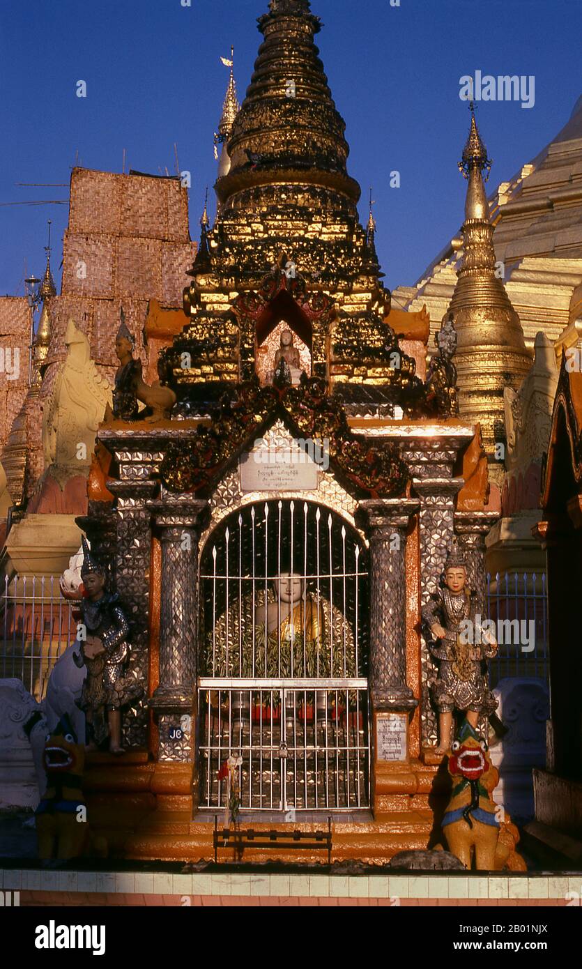 Birma/Myanmar: Buddha-Bild in einer kleineren Stupa um den Fuß der Shwedagon-Pagode, Yangon (Rangun). Die goldene Stupa der Shwedagon-Pagode erhebt sich fast 100 m (330 ft) über ihrer Lage auf dem Singuttara Hill und ist mit 8.688 massiven Goldplatten überzogen. Diese zentrale Stupa ist von mehr als 100 anderen Gebäuden umgeben, darunter kleinere Stupas und Pavillons. Die Pagode war bereits gut etabliert, als Bagan Burma im 11. Jahrhundert dominierte. Königin Shinsawbu, die im 15. Jahrhundert regierte, soll der Pagode ihre heutige Form gegeben haben. Stockfoto