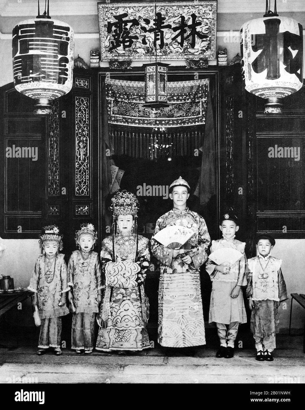 Malaysia/Singapur: Eine Braut und ein Bräutigam aus Penang posieren für ihr Hochzeitsfoto vor dem Haus der Familie, Anfang des 20. Jahrhunderts. Peranakan Chinese und Baba-Nyonya sind die Bezeichnungen für die Nachkommen chinesischer Einwanderer aus dem späten 15. Und 16. Jahrhundert, die während der Kolonialzeit in den malaiisch-indonesischen Archipel von Nusantara kamen. Mitglieder dieser Gemeinde in Malaysia bezeichnen sich als „Nyonya-Baba“ oder „Baba-Nyonya“. Nyonya ist der Begriff für die Weibchen und Baba für die Männchen. Sie gilt insbesondere für die ethnische chinesische Bevölkerung der British Straits Settlements in Malaya. Stockfoto