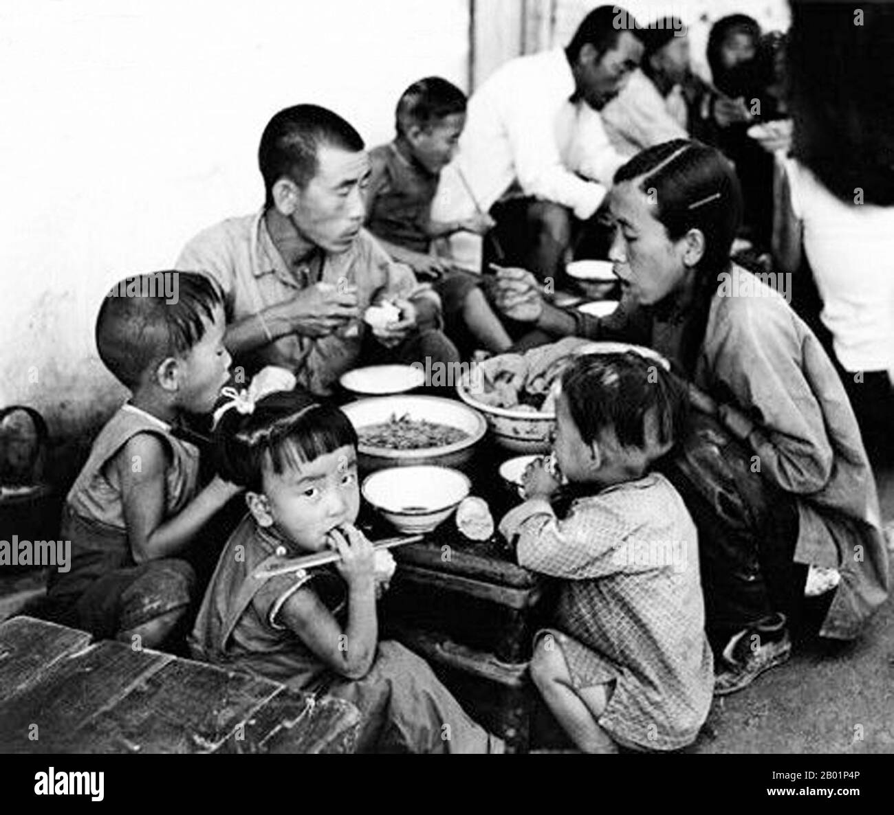 China: Bauernfamilien essen während des Großen Vorwärtssprungs (1958–1961) in einer Gemeinde. Der große Sprung nach vorne in der Volksrepublik China (VR China) war eine wirtschaftliche und soziale Kampagne der Kommunistischen Partei Chinas (KPC), die sich in Planungsentscheidungen von 1958 bis 1961 widerspiegelte. die darauf abzielte, Chinas riesige Bevölkerung zu nutzen, um das Land durch den Prozess der raschen Industrialisierung und Kollektivierung rasch von einer Agrarwirtschaft in eine moderne kommunistische Gesellschaft zu verwandeln. Mao Zedong leitete die Kampagne auf der Grundlage der Theorie der produktiven Kräfte. Stockfoto