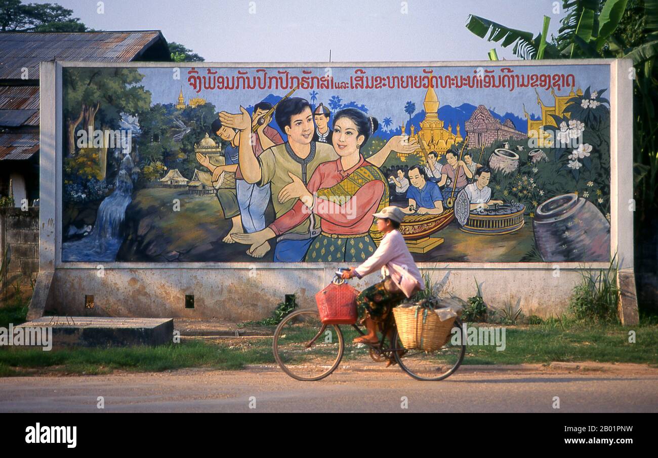 Laos: "Traditionelle Kultur im Einklang mit sozialistischen Prinzipien", politisches Poster im revolutionären sozialistischen Realismus auf den Straßen von Vientiane. Der sozialistische Realismus ist ein Stil realistischer Kunst, der in der Sowjetunion entwickelt wurde und in anderen kommunistischen Ländern zu einem dominierenden Stil wurde. Der sozialistische Realismus ist ein teleologisch orientierter Stil, dessen Ziel die Förderung der Ziele des Sozialismus und des Kommunismus ist. Obwohl sie damit verbunden ist, darf sie nicht mit dem sozialen Realismus verwechselt werden, einer Art von Kunst, die Themen sozialer Belange realistisch darstellt. Stockfoto