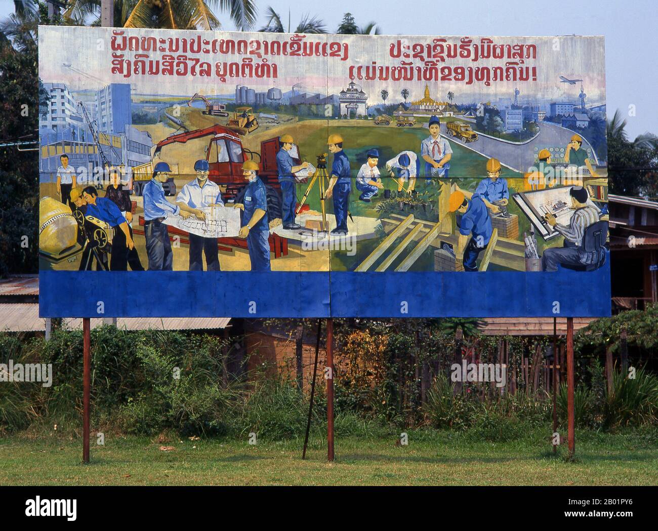 Laos: Bau und Industrie in Laos. Revolutionäres sozialistisches Poster auf den Straßen von Vientiane. Der sozialistische Realismus ist ein Stil realistischer Kunst, der in der Sowjetunion entwickelt wurde und in anderen kommunistischen Ländern zu einem dominierenden Stil wurde. Der sozialistische Realismus ist ein teleologisch orientierter Stil, dessen Ziel die Förderung der Ziele des Sozialismus und des Kommunismus ist. Obwohl sie damit verbunden ist, darf sie nicht mit dem sozialen Realismus verwechselt werden, einer Art von Kunst, die Themen sozialer Belange realistisch darstellt. Stockfoto