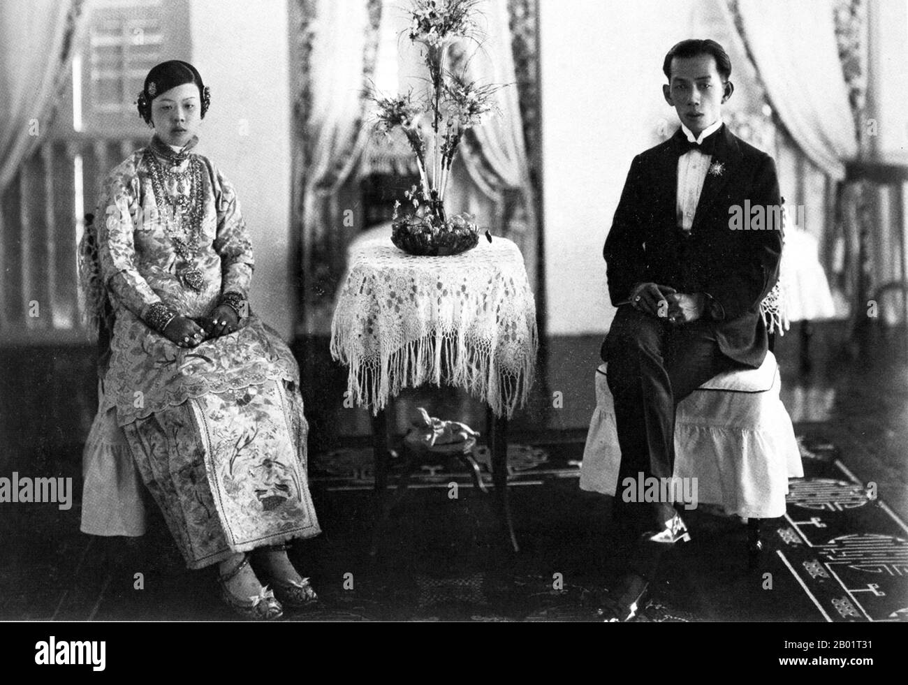 Malaysia/Singapur: Eine Peranakan Braut und Bräutigam in ihrer Brautkammer, Penang, um 1920. Peranakan Chinese und Baba-Nyonya sind die Bezeichnungen für die Nachkommen chinesischer Einwanderer aus dem späten 15. Und 16. Jahrhundert, die während der Kolonialzeit in den malaiisch-indonesischen Archipel von Nusantara kamen. Mitglieder dieser Gemeinde in Malaysia bezeichnen sich als „Nyonya-Baba“ oder „Baba-Nyonya“. Nyonya ist der Begriff für die Weibchen und Baba für die Männchen. Sie gilt insbesondere für die ethnischen chinesischen Bevölkerungsgruppen der British Straits Settlements in Malaya und der von den Niederlanden kontrollierten Insel Java und anderen Orten. Stockfoto