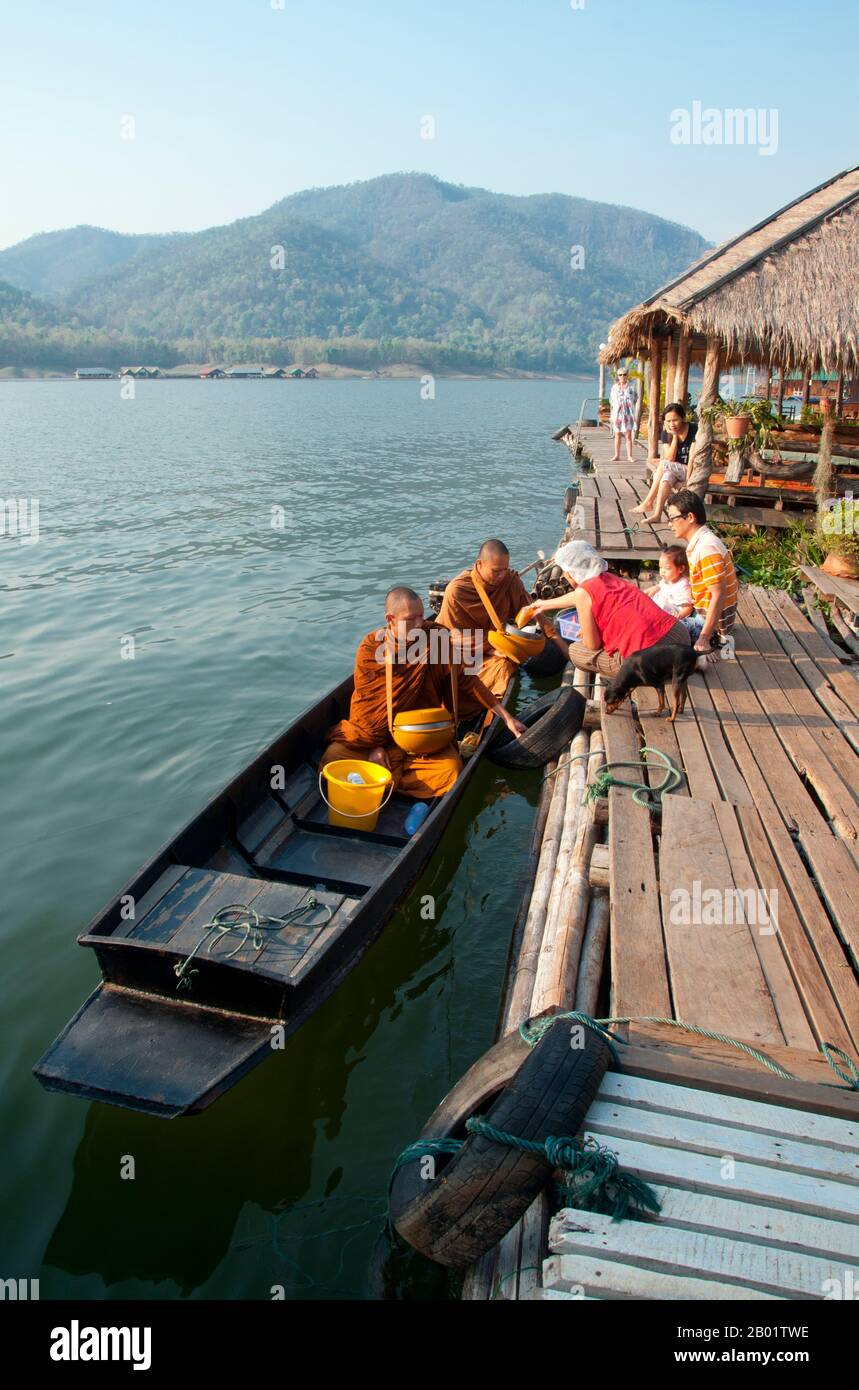 Thailand: Mönche auf ihrem frühen Morgengrauen auf dem See am Mae Ngat Dam, in der Nähe von Chiang Mai, Nordthailand. Im Theravada-Buddhismus gehen Mönche und Nonnen täglich auf eine Almosenrunde (oder Pindacara), um Nahrung zu sammeln. Dies wird oft so wahrgenommen, als gäbe es Laien die Möglichkeit, Verdienste zu machen. Geld sollte nicht von buddhistischen Mönchen oder Nonnen angenommen werden, anstatt oder zusätzlich zu Essen. obwohl heutzutage nicht viele Mönche und Nonnen diese Regel einhalten (mit Ausnahme der Mönche und Nonnen der Thai Forest Tradition und anderer Theravada Traditionen, die sich auf vinaya und Meditationspraxis konzentrieren). Stockfoto