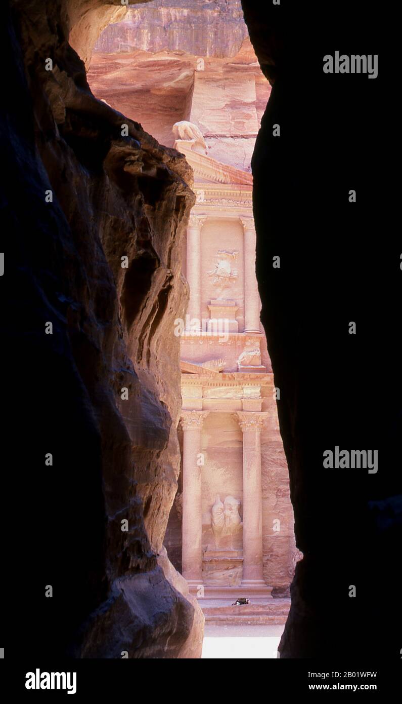 Jordanien: Siq (Schacht) und Al Khazneh (Schatzkammer) im Hintergrund, Petra. Der Siq oder al-Siq („der Schacht“) ist der Haupteingang zur antiken Stadt Petra im südlichen Jordanien. Die dunkle, schmale Schlucht (an einigen Stellen nicht mehr als 3 Meter breit) windet sich etwa 1,5 km und endet bei Petras aufwändigster Ruine, Al Khazneh (die Schatzkammer). Petra wurde im 4. Jahrhundert v. Chr. von den nabatäischen Arabern als Stadt gegründet und verdankt seine Geburt und seinen Wohlstand der Tatsache, dass es der einzige Ort mit klarem und reichlich Wasser zwischen den Hijaz-Handelszentren Mekka und Medina war. Stockfoto
