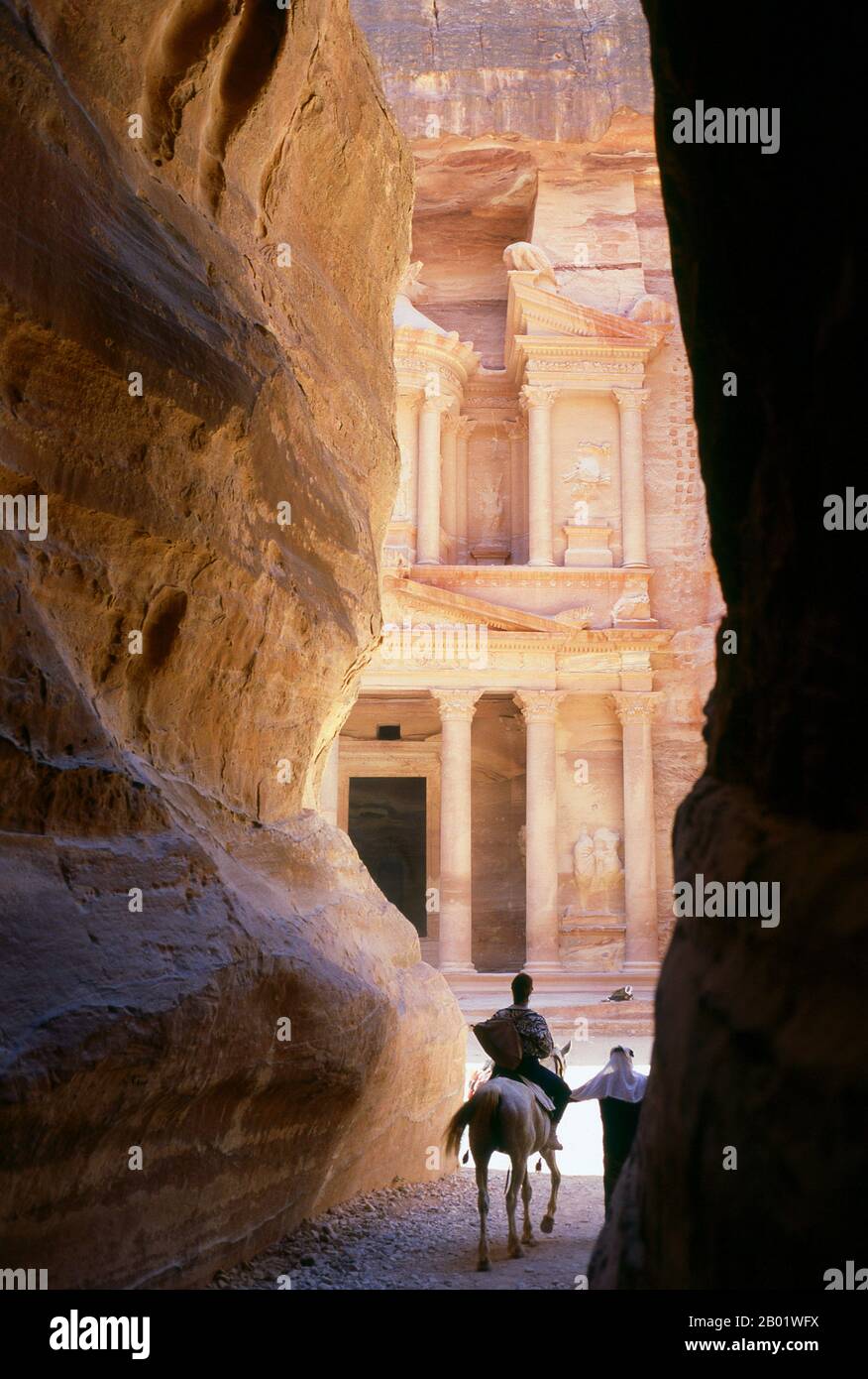 Jordanien: Siq (Schacht) und Al Khazneh (Schatzkammer) im Hintergrund, Petra. Der Siq oder al-Siq („der Schacht“) ist der Haupteingang zur antiken Stadt Petra im südlichen Jordanien. Die dunkle, schmale Schlucht (an einigen Stellen nicht mehr als 3 Meter breit) windet sich etwa 1,5 km und endet bei Petras aufwändigster Ruine, Al Khazneh (die Schatzkammer). Petra wurde im 4. Jahrhundert v. Chr. von den nabatäischen Arabern als Stadt gegründet und verdankt seine Geburt und seinen Wohlstand der Tatsache, dass es der einzige Ort mit klarem und reichlich Wasser zwischen den Hijaz-Handelszentren Mekka und Medina war. Stockfoto