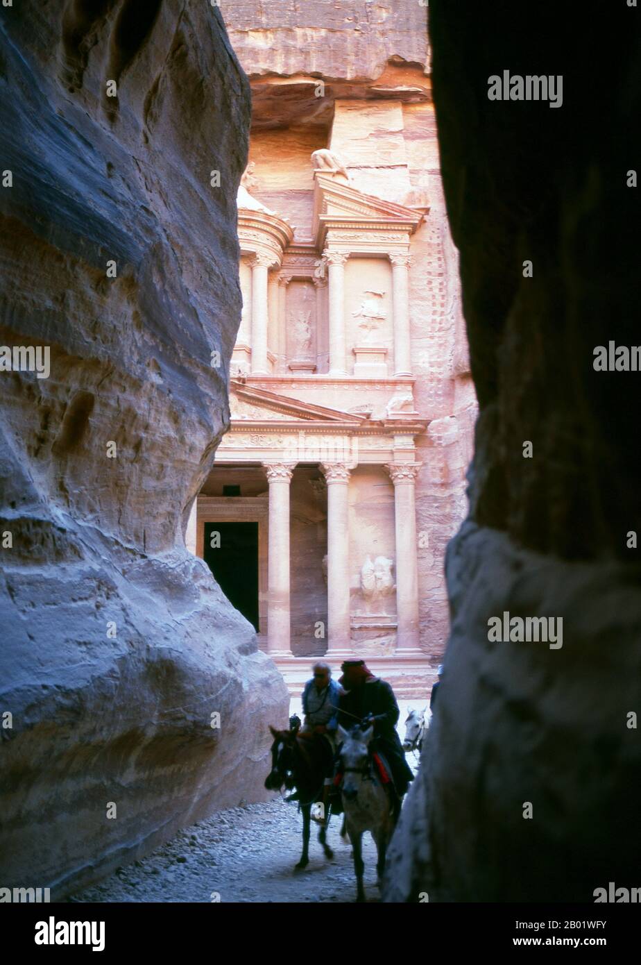 Jordanien: Siq (Schacht) und Al Khazneh (Schatzkammer) im Hintergrund, Petra. Der Siq oder al-Siq („der Schacht“) ist der Haupteingang zur antiken Stadt Petra im südlichen Jordanien. Die dunkle, schmale Schlucht (an einigen Stellen nicht mehr als 3 Meter breit) windet sich etwa 1,5 km und endet bei Petras aufwändigster Ruine, Al Khazneh (die Schatzkammer). Petra wurde im 4. Jahrhundert v. Chr. von den nabatäischen Arabern als Stadt gegründet und verdankt seine Geburt und seinen Wohlstand der Tatsache, dass es der einzige Ort mit klarem und reichlich Wasser zwischen den Hijaz-Handelszentren Mekka und Medina war. Stockfoto