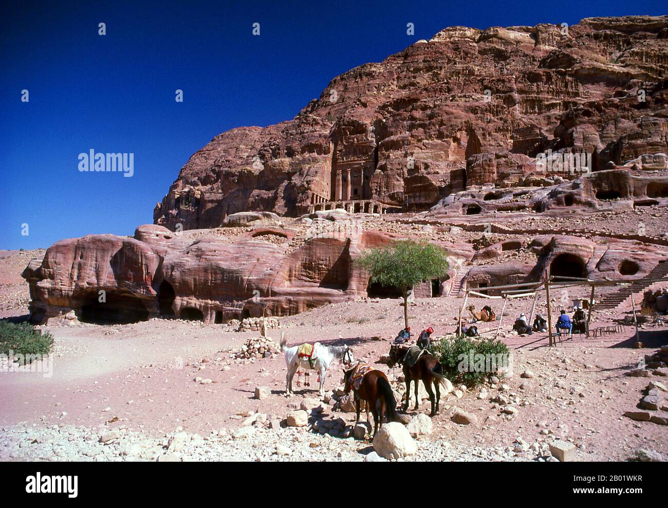 Jordanien: Arabische Reiter vor dem Urnengruft Petra. Petra wurde im 4. Jahrhundert v. Chr. von den nabatäischen Arabern als Stadt gegründet und verdankt seine Geburt und seinen Wohlstand der Tatsache, dass es der einzige Ort mit klarem und reichlich Wasser zwischen den Hidschas-Handelszentren Mekka und Medina und Palästina war. Direkt in die nubischen Sandsteinkämme der südjordanischen Wüste gehauen, scheint es wahrscheinlich, dass Petra aufgrund seiner hervorragenden Verteidigungslage und der guten Wasserversorgung seit der paläolithischen Zeit fortwährend besetzt wurde. Es wird vermutet, dass es in der Bibel erwähnt wird. Stockfoto