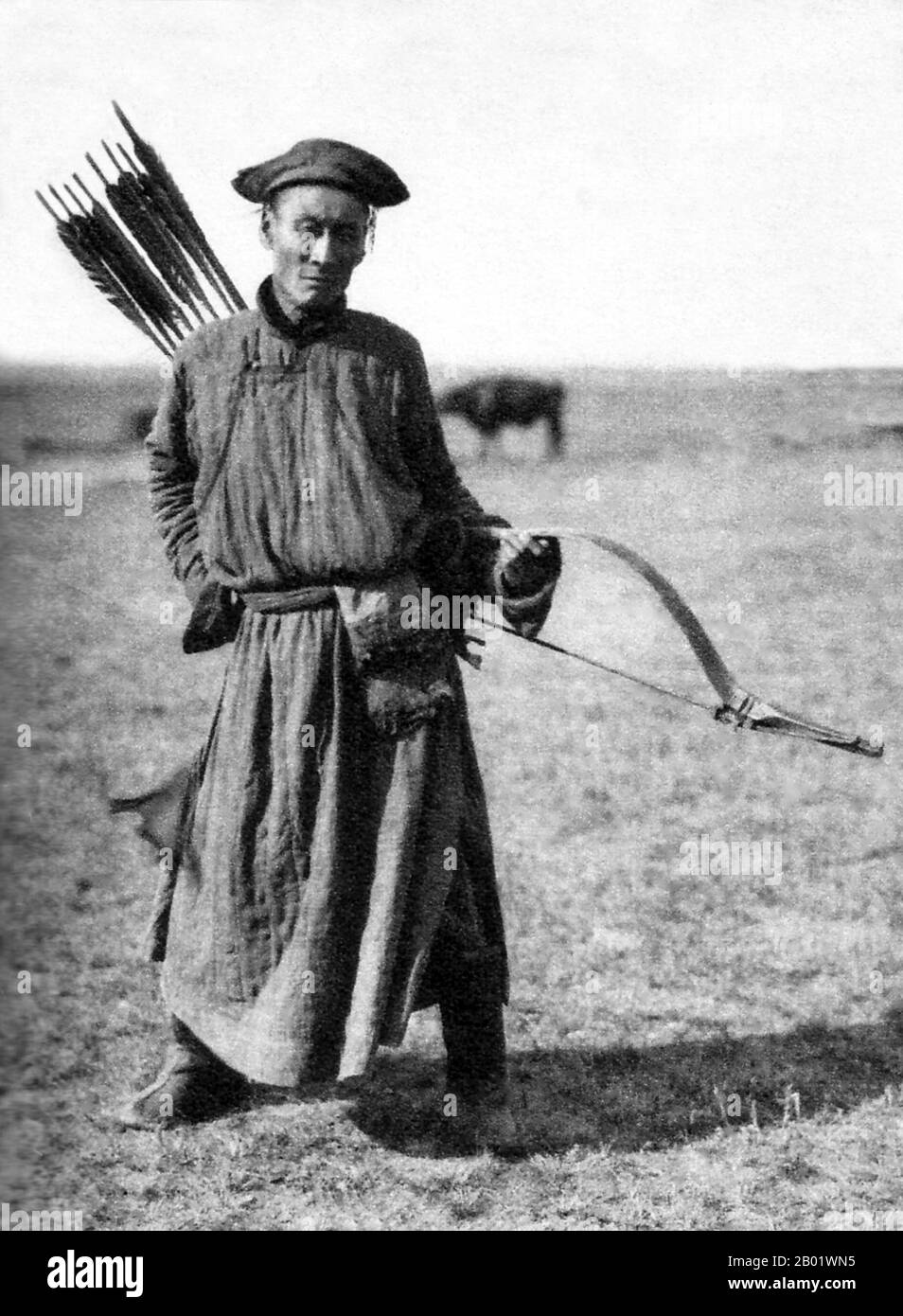 China/Innere Mongolei: Ein traditioneller mongolischer Bogenschütze im Innern Mongolischen Grasland, um 1940. Vorderansicht. Der mongolische Bogen ist ein wiederkehrender Verbundbogen, der für seine militärische Wirksamkeit bekannt ist. Die alten mongolischen Bögen, die während der Zeit von Dschingis Khan verwendet wurden, waren kleiner als die modernen Waffen, die heute auf den meisten Naadam-Festivals verwendet wurden. Moderne mongolische Bögen sind größer und haben Schnur-Brücken. Das moderne Design ähnelt sehr den mandschurischen Bögen, die das chinesische Militär während der Qing-Dynastie verwendet hat. Antike und moderne mongolische Bögen sind Teil der asiatischen Tradition von Verbundbögen. Stockfoto
