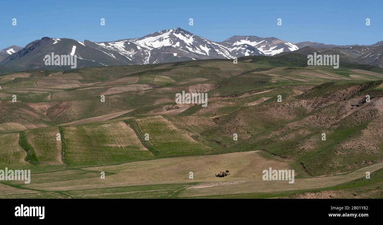 Panorama auf Takht-e Soleyman mit landwirtschaftlichen Feldern, Hügeln und schneebedeckten Bergen im Iran. Stockfoto