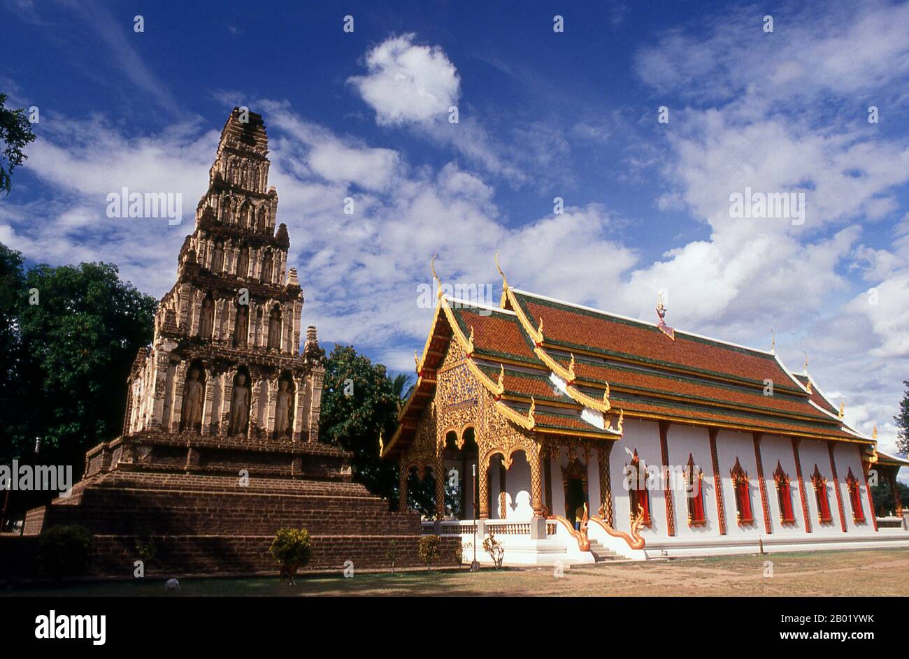 Thailand: Chedi Suwant Chang Kot (oder Mahapon Chedi) und Viharn, Wat Chama Thewi, Lamphun, Nordthailand. Wat Chamathewi (Chama Thewi oder Chamadevi) oder Wat Kukut (Tempel der gebrochenen Reliquien), wie er auch genannt wird, wurde irgendwann im 8. Oder 9. Jahrhundert erbaut. Es enthält zwei authentische Mon Chedi. Der erste und größere davon ist der Mahapon Chedi oder „Great Victory Stupa“, auch bekannt als Chedi Suwant Chang Kot oder „Heavenly Stupa with a herrlich Summit“, eine hohe Struktur aus Laterit und Stuck, die auf einem quadratischen Lateritfundament aufgestellt ist. Stockfoto