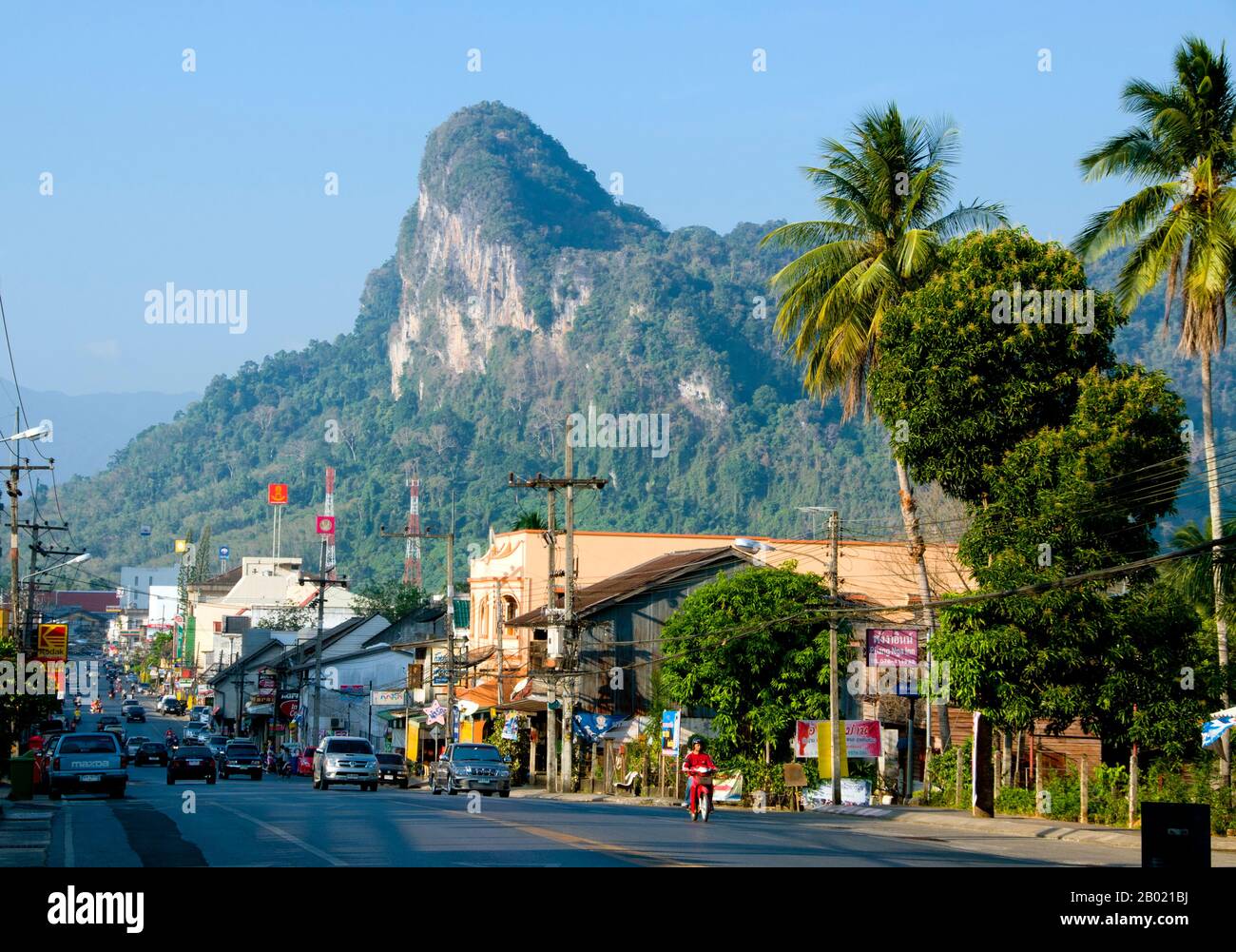 Thailand: Kalksteingipfel erheben sich über der Hauptstraße von Phangnga Town. Phang Nga Town, die Hauptstadt der Provinz Phang Nga, ist eine ziemlich heruntergekommene Stadt in einer spektakulären Lage, die immer im Schatten des boomenden benachbarten Phuket steht. In der Umgebung gibt es viel zu tun und zu sehen, vor allem in der wunderschönen Phang Nga Bay, aber nur wenige Besucher werden sich für einen Aufenthalt in der Stadt entscheiden, da es in den nahe gelegenen Strandresorts von Phuket Island eine verlockende - und offen gesagt viel komfortablere - Unterkunft gibt. Stockfoto