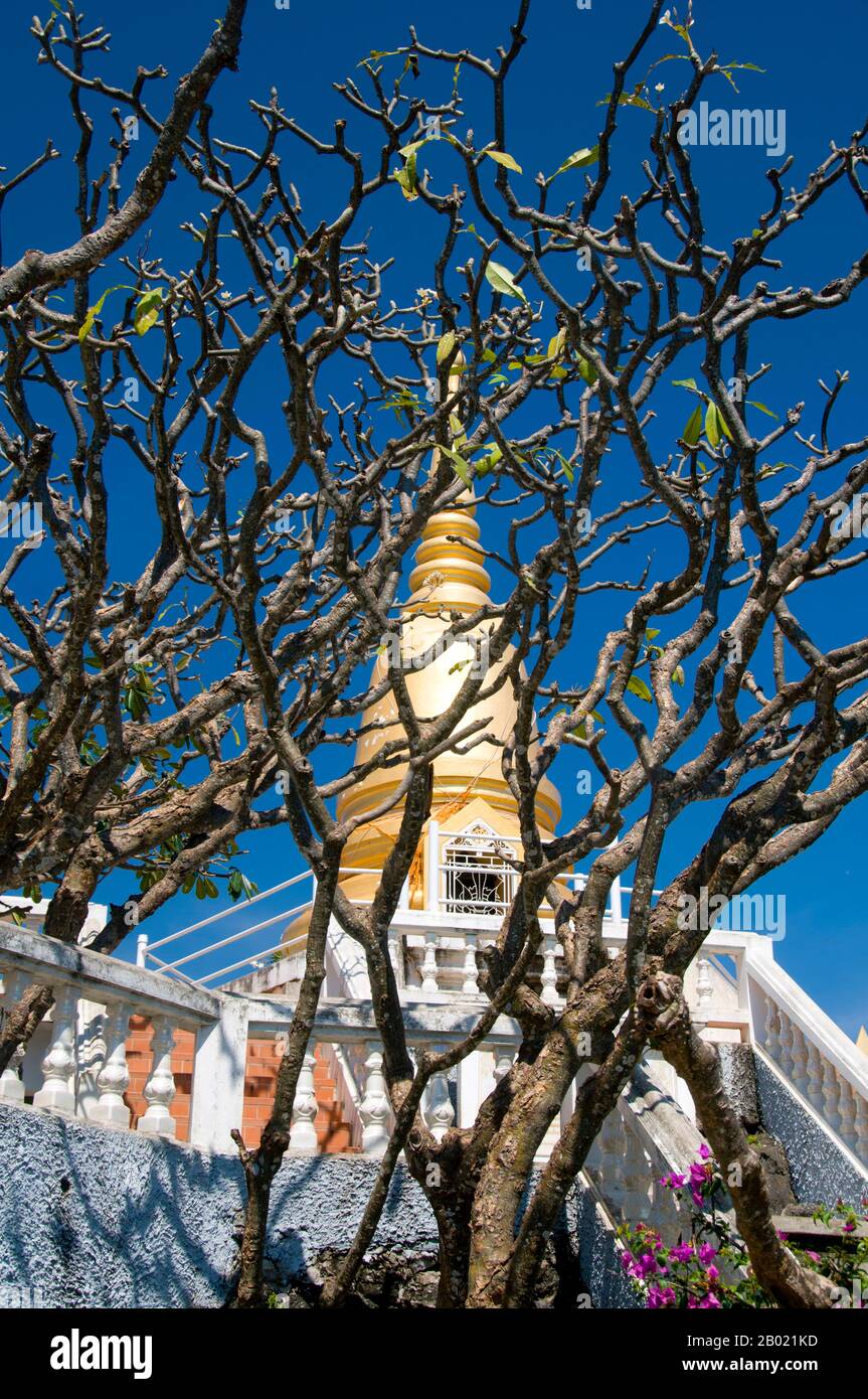 Thailand: Chedi- und Frangipani-Bäume, Wat Thammikaram, Khao Chong Krajok (Spiegelberg), Prachuap Khiri Khan. Prachuap Khiri Khan bedeutet „Stadt unter der Bergkette“. Obwohl die Stadt etwas mehr als ein Fischerhafen ist, hat sie - je nachdem, mit wem man spricht - einen ganz besonderen Charme und liegt abseits der Touristenpfade. Das heißt, Touristen fahren die ganze Zeit durch, aber sie halten selten an. Stockfoto