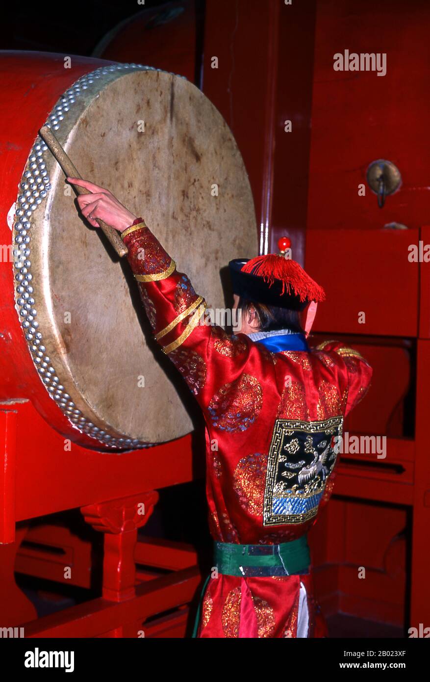 China: Zeremonieller Schlagzeuger im Trommelturm (Gulou), Peking. Der Trommelturm (Gǔlóu) und der Glockenturm (Zhōnglóu) wurden 1272 während der Regierungszeit von Kublai Khan (R. 1260–1294) errichtet. Kaiser Yongle (R. 1402–1424) baute die Türme 1420 wieder auf und sie wurden während der Regierungszeit des Qing-Kaisers Jiaqing (R. 1796–1820) wieder renoviert. Sowohl der Drum- als auch der Glockenturm wurden während der Yuan-, Ming- und Qing-Dynastien als Zeitmesser genutzt. Stockfoto