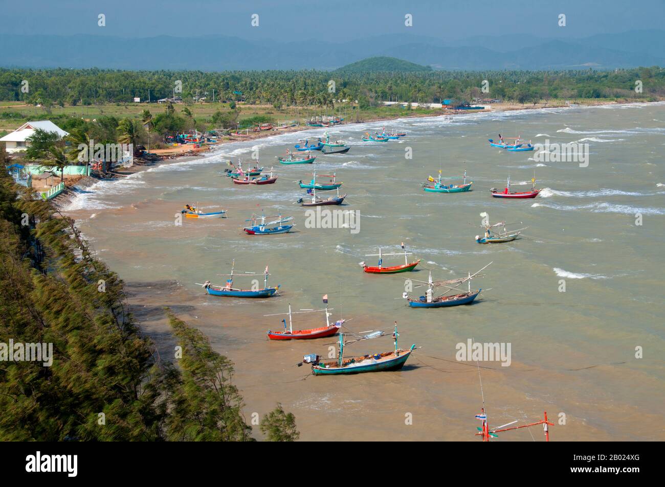 Thailand: Fischerboote vom Wat Khao Tham Khan Kradai aus gesehen, Provinz Prachuap Khiri Khan. Wat Khao Tham Khan Kradai ist ein buddhistischer Höhlentempel, der sich über einer wunderschönen Bucht nördlich von Prachuap Khiri Khan befindet. Ein ausgeschilderter Pfad am Fuße eines Kalksteinhügels mit Blick auf die Khan Kradai Bucht führt an der Seite des Hügels zu einer kleinen Höhle, die wiederum zu einer größeren Höhle führt, in der ein phra non oder ein liegender Buddha untergebracht ist. Darüber hinaus befindet sich eine weitere Kammer, die ähnlich gefüllt ist mit Buddha-Bildern, die von den Gläubigen in Akten der Verdienste gebracht und hinterlassen wurden. Stockfoto
