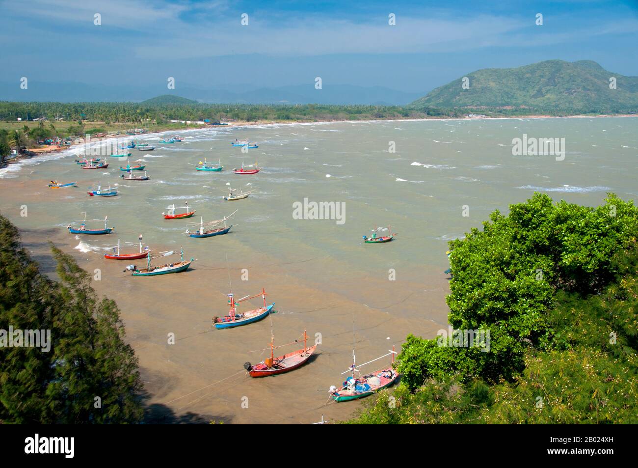 Thailand: Fischerboote vom Wat Khao Tham Khan Kradai aus gesehen, Provinz Prachuap Khiri Khan. Wat Khao Tham Khan Kradai ist ein buddhistischer Höhlentempel, der sich über einer wunderschönen Bucht nördlich von Prachuap Khiri Khan befindet. Ein ausgeschilderter Pfad am Fuße eines Kalksteinhügels mit Blick auf die Khan Kradai Bucht führt an der Seite des Hügels zu einer kleinen Höhle, die wiederum zu einer größeren Höhle führt, in der ein phra non oder ein liegender Buddha untergebracht ist. Darüber hinaus befindet sich eine weitere Kammer, die ähnlich gefüllt ist mit Buddha-Bildern, die von den Gläubigen in Akten der Verdienste gebracht und hinterlassen wurden. Stockfoto