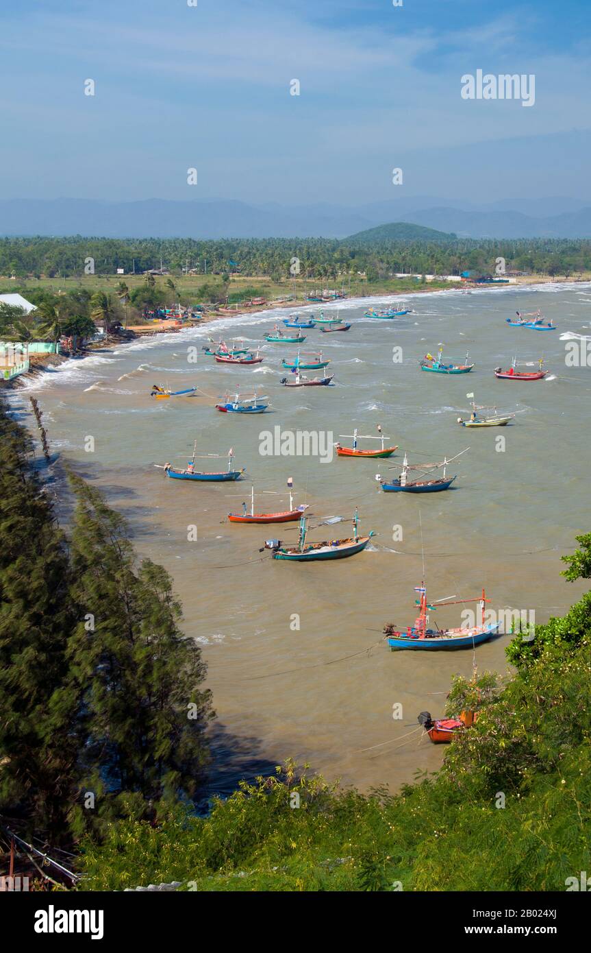 Thailand: Fischerboote vom Wat Khao Tham Khan Kradai aus gesehen, Provinz Prachuap Khiri Khan. Wat Khao Tham Khan Kradai ist ein buddhistischer Höhlentempel, der sich über einer wunderschönen Bucht nördlich von Prachuap Khiri Khan befindet. Ein ausgeschilderter Pfad am Fuße eines Kalksteinhügels mit Blick auf die Khan Kradai Bucht führt an der Seite des Hügels zu einer kleinen Höhle, die wiederum zu einer größeren Höhle führt, in der ein phra non oder ein liegender Buddha untergebracht ist. Darüber hinaus befindet sich eine weitere Kammer, die ähnlich gefüllt ist mit Buddha-Bildern, die von den Gläubigen in Akten der Verdienste gebracht und hinterlassen wurden. Stockfoto