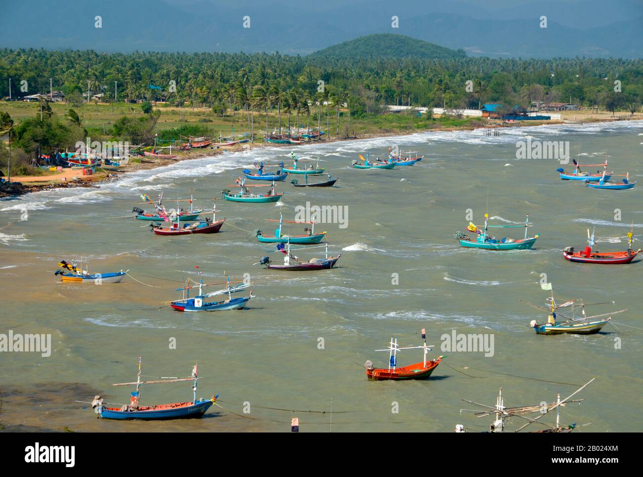 Thailand: Fischerboote vom Wat Khao Tham Khan Kradai aus gesehen, Provinz Prachuap Khiri Khan. Wat Khao Tham Khan Kradai ist ein buddhistischer Höhlentempel, der sich über einer wunderschönen Bucht nördlich von Prachuap Khiri Khan befindet. Ein ausgeschilderter Pfad am Fuße eines Kalksteinhügels mit Blick auf die Khan Kradai Bucht führt an der Seite des Hügels zu einer kleinen Höhle, die wiederum zu einer größeren Höhle führt, in der ein phra non oder ein liegender Buddha untergebracht ist. Darüber hinaus befindet sich eine weitere Kammer, die ähnlich gefüllt ist mit Buddha-Bildern, die von den Gläubigen in Akten der Verdienste gebracht und hinterlassen wurden. Stockfoto