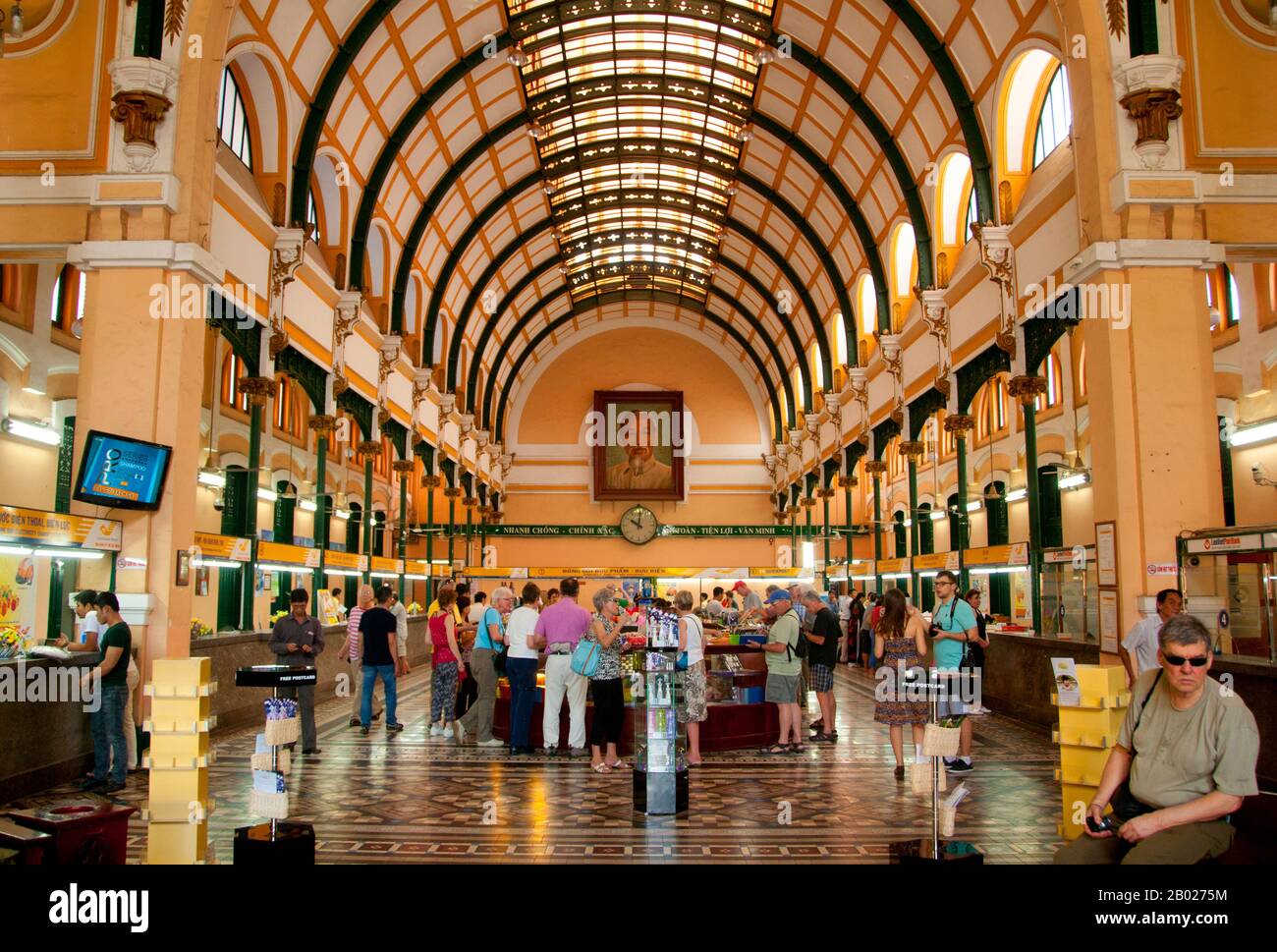 Vietnam: Ein riesiges Porträt von Ho Chi Minh untersucht das Innere des französischen Kolonialpostamtes Saigon (Ho Chi Minh City). Das General Post Office von Saigon, neben der Kathedrale Notre Dame, wurde zwischen 1886 und 1891 erbaut. Das von Gustave Eiffel (dem berühmten Eiffelturm) entworfene Innenraum erinnert an einen großen europäischen Bahnhof aus dem 19. Jahrhundert. Der ehemalige Kaiser Bảo Đại machte Saigon 1949 mit sich selbst als Staatsoberhaupt zur Hauptstadt des Staates Vietnam. Stockfoto