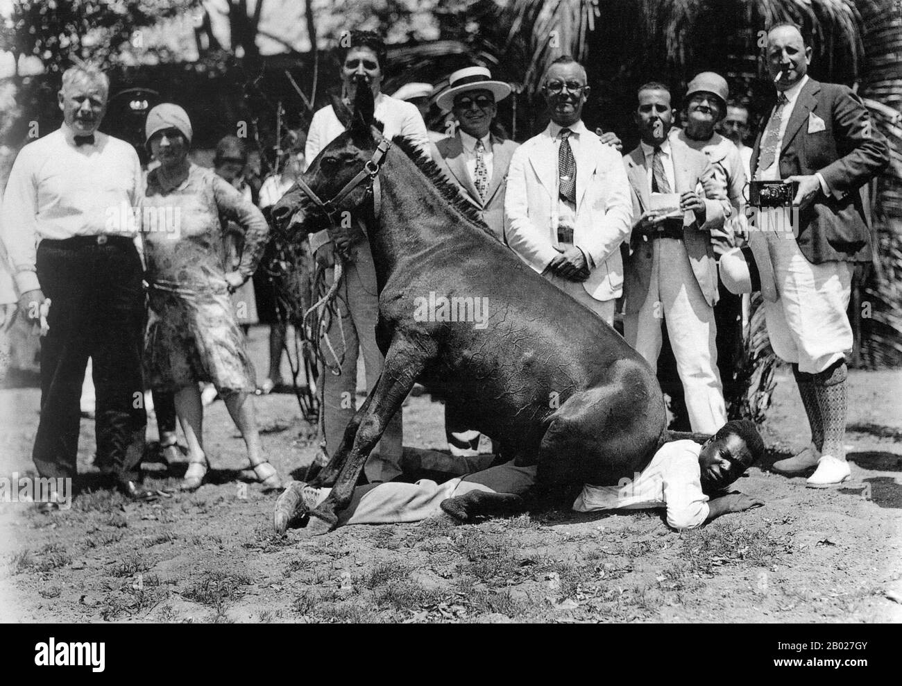 Kuba: Rassenbeziehungen in Kuba, Santiago de Cuba, 1927. Ein Pferd sitzt auf einem schwarzen Mann, während wohlhabende Weiße lächelnd zuschauen. Die Bevölkerung Kubas hat sehr komplexe Ursprünge, und die Verheiratung zwischen verschiedenen Gruppen ist allgemein. Es gibt Meinungsverschiedenheiten über Rassenstatistiken. Das Institut für kubanische und kubanisch-amerikanische Studien an der Universität Miami sagt, dass 62 % schwarz sind, während Statistiken der kubanischen Volkszählung besagen, dass 2002 65 % der Bevölkerung weiß waren. Stockfoto