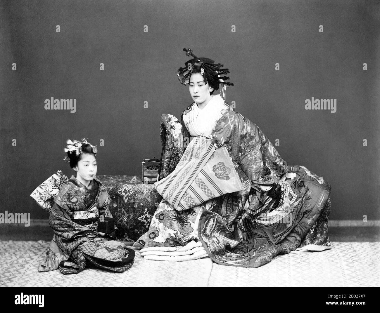 Japan: Studio-Porträt einer wohlhabenden Geisha im Kimono mit ihrem Maiko-Assistenten des japanischen Fotografen Ueno Hikoma (15. Oktober 1838 bis 22. Mai 1904), ca. 1868. Ueno Hikoma war ein japanischer Fotograf, der in Nagasaki geboren wurde. Er ist bekannt für seine schönen Porträts, oft von bedeutenden japanischen und ausländischen Persönlichkeiten, und für seine ausgezeichneten Landschaften, besonders von Nagasaki und seiner Umgebung. Ueno war eine der Hauptfiguren der japanischen Fotografie des 19. Jahrhunderts als kommerziell und künstlerisch erfolgreicher Fotograf und als Ausbilder. Stockfoto