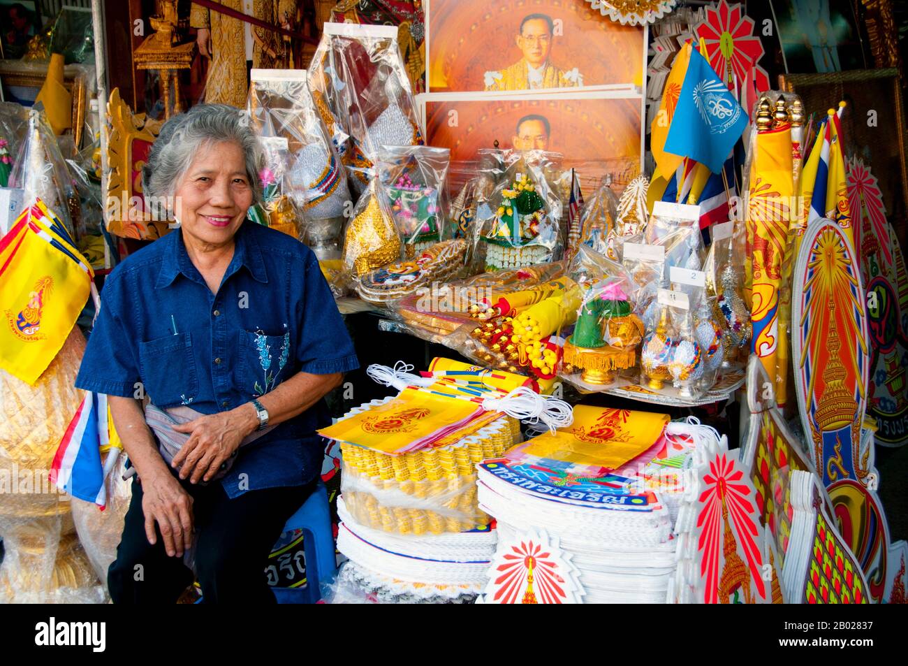 Thailand: Eine thailändische Frau verkauft königliche Gegenstände, einschließlich gelber königlicher Flaggen für König Bhumibol (Rama IX) in Banglamphu, Bangkok. Bhumibol Adulyadej (Phumiphon Adunyadet; 5. Dezember 1927 - 13. Oktober 2016) war der König von Thailand. Er war bekannt als Rama IX (und innerhalb der thailändischen Königsfamilie und enger Partner einfach als Lek. Seit dem 9. Juni 1946 regierte er als der längste regierende Monarch der thailändischen Geschichte. Stockfoto