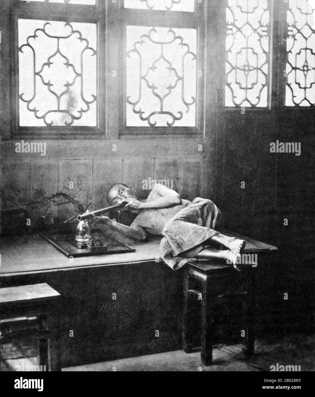 China: Opium Rauchen in einem Restaurant. Foto von John Thomson (1837-1921), 1874. Opiummohn, Papaver somniferum, ist die Pflanzenart, aus der Opium und Mohn gewonnen werden. Opium ist die Quelle vieler Opiate, einschließlich Morphin, Thebain, Codein, Papaverin, und Noscapin. Der lateinische botanische Name bedeutet „schlafenden Mohn“ und bezieht sich auf die sedierenden Eigenschaften einiger dieser Opiate. Stockfoto