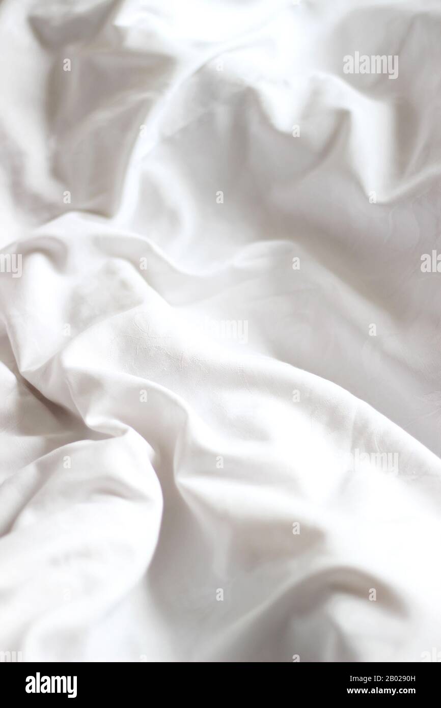 Weiße, Zerknitterte Blätter auf einem Unfertigen Bett. Weißer Textilhintergrund mit Kopierbereich. Stockfoto