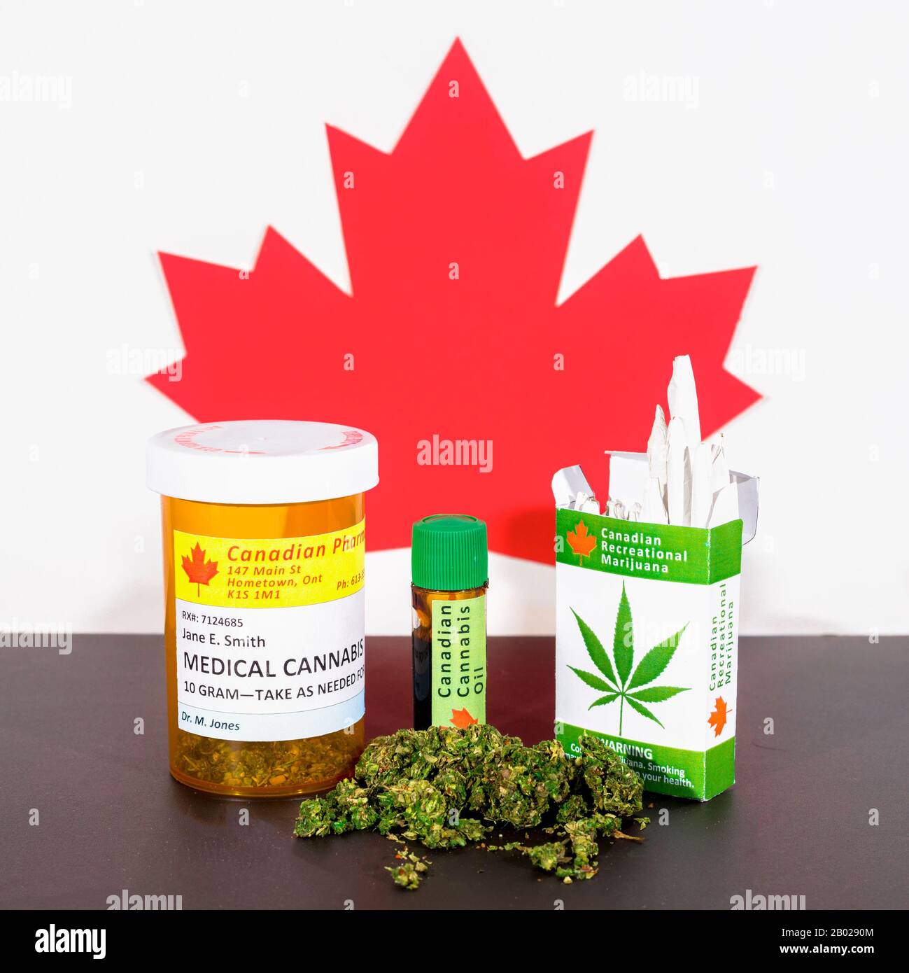 Cannabis in Kanada. Medizinisches Cannabis, Cannabisöl, Knospen und ein Paket Cannabiszigaretten auf einem Tisch, hinter dem ein kanadisches Ahorn-Blatt steht. Stockfoto