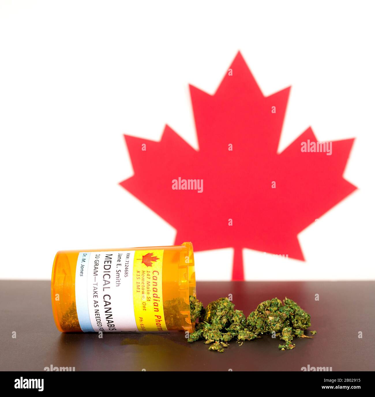 Cannabis in Kanada. Die medizinische Verwendung von Cannabis Verschütten von einer Verordnung Flasche auf einem Tisch, mit einem Kanadischen maple leaf hinter sich. Marihuana Knospen auf den Tisch. Stockfoto