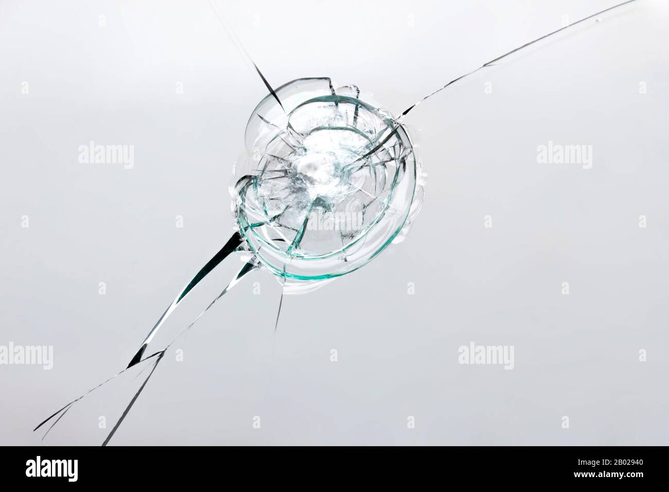 Risse auf zerbrochenem Glas durch Aufprall, weißer Rispenbrunnen auf dem Fenster. Stockfoto