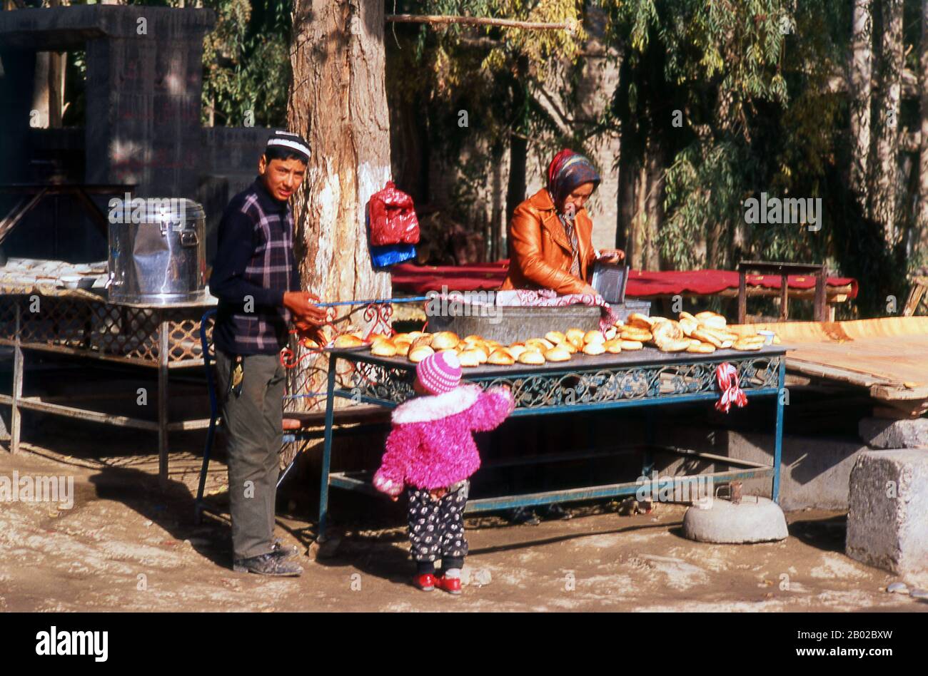 China: Brotverkäufer in einer kleinen Oasenstadt in der Nähe von Khotan, Provinz Xinjiang. Von der niederländischen Brut, dem Deutschen brot und der friesischen Brasse ist das Alte Englische Brot ein weltweit beliebtes und so alt wie die organisierte Zivilisation. Es ist das Grundnahrungsmittel in Europa und in Europa beeinflussten Kulturen in Amerika, Afrika und dem Nahen Osten, im Gegensatz zur Bedeutung von Reis in Ost- und Südostasien. Khotan geht seine Geschichte mindestens bis ins 3. Jahrhundert v. Chr. zurück, als sich hier der älteste Sohn des indischen Kaisers Asoka niedergelassen hat. Stockfoto