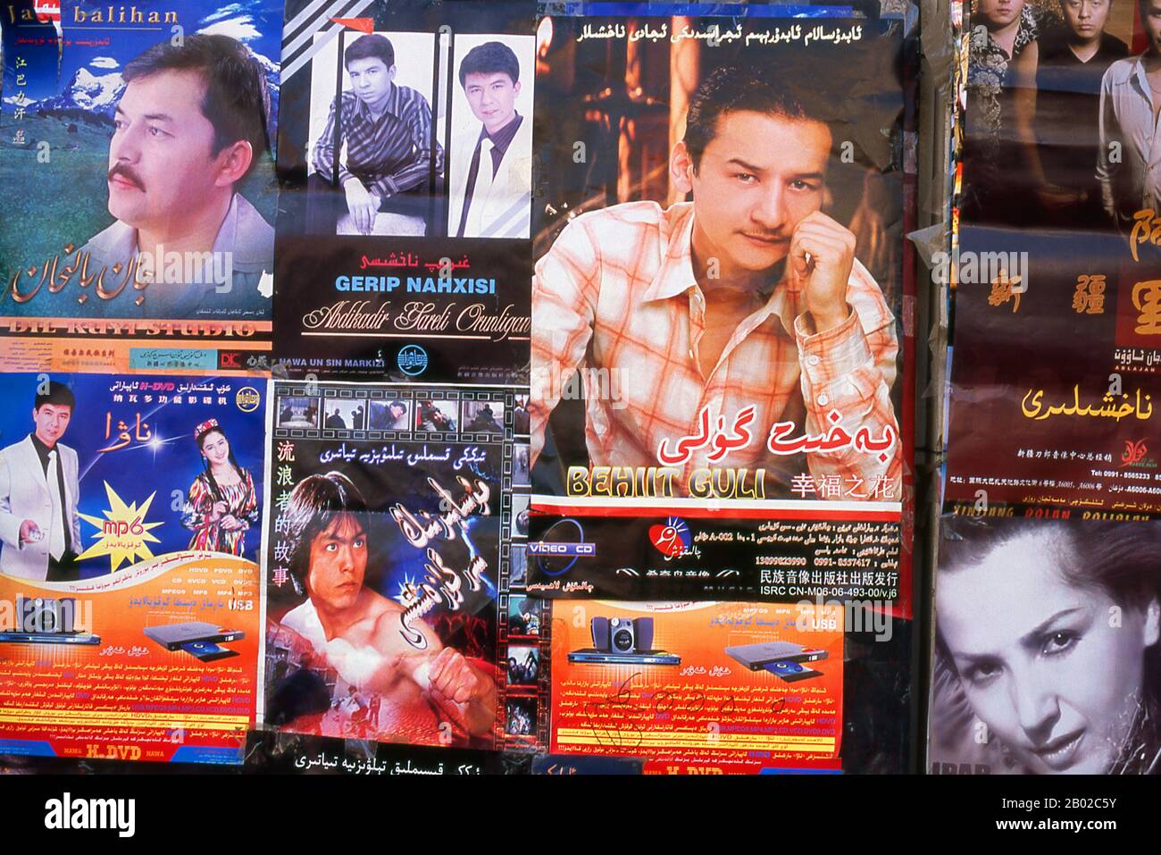 China: Filmplakate an einer Wand in Khotan, Provinz Xinjiang. Khotan geht seine Geschichte mindestens bis ins 3. Jahrhundert v. Chr. zurück, als sich hier der älteste Sohn des indischen Kaisers Asoka niedergelassen hat. Sie war von großer Bedeutung auf der Seidenstraße und soll der erste Ort außerhalb Chinas gewesen sein, an dem Seide angebaut wurde. Er liegt auf den Flüssen Karakash oder Black Jade und Yurungkash oder White Jade, die sich hier zum Khotan Darya verbinden und seit weit über zwei Jahrtausenden berühmt für seine Jade sind. Stockfoto