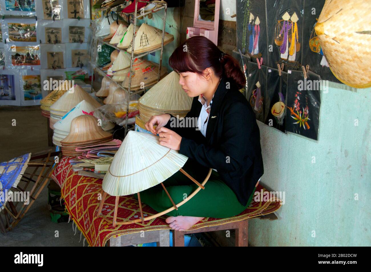 Vietnam: Ein non la (vietnamesischer konischer Hut) Hersteller, Thuy Xuan Räucherwerk Dorf, Hue. Der allgegenwärtige cremefarbene Non la (konischer Hut) schützt Bauern vor tropischer Sonne und Monsunregen wie ein mobiler Sonnenschirm. Der Hut besteht aus Latania-Palmblättern, die um eine Bambuslatte gewebt sind. Heute tragen weit mehr Frauen als Männer die emblematischen Kopfbedeckungen. Stockfoto