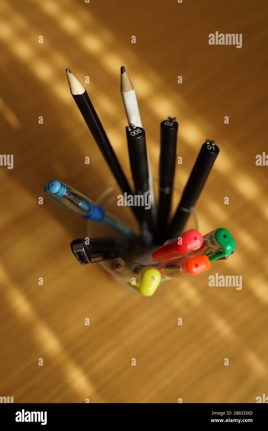 Bürobedarf auf einem Holztisch. Farbige Bleistifte und Kugelschreiber in einem Ständer. Stockfoto