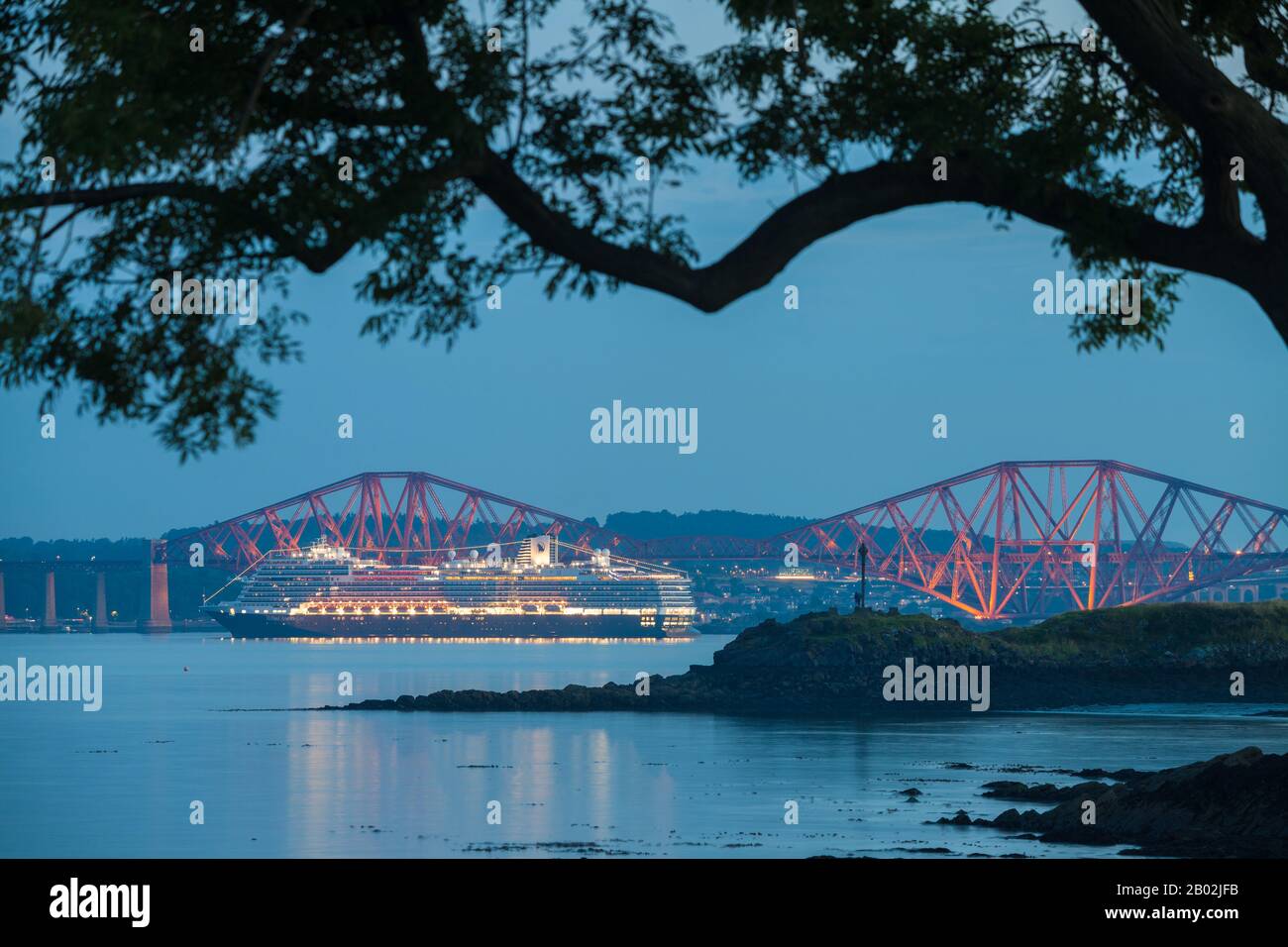 Ein Kreuzfahrtschiff zündete nachts unter der Forth Rail Bridge in der Nähe von Edinburgh Scotland an. Stockfoto