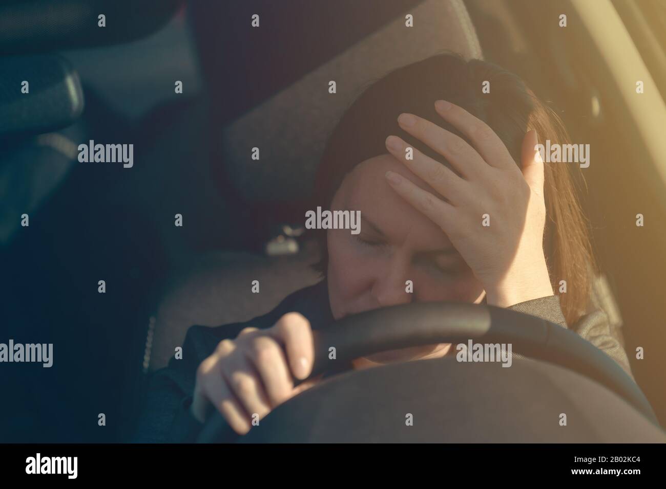 Enttäuschte Geschäftsfrau im Auto, packte das Fahrzeuglenkrad und hielt ihren Kopf ungläubig, selektiv im Fokus Stockfoto