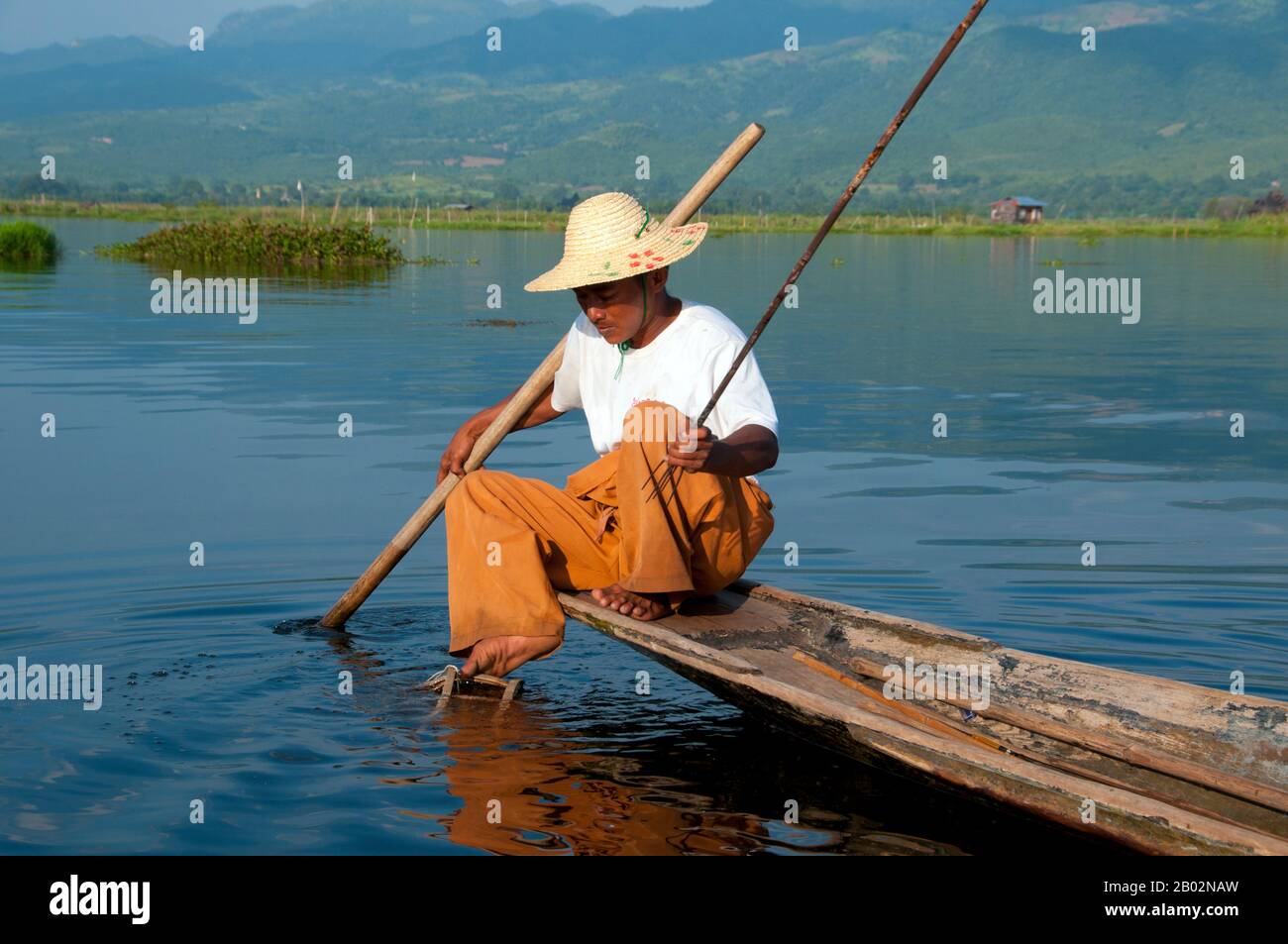 Der Inle Lake (116 km2) ist flach, lang, kristallklar und ruhig. Hier leben die Intha-Menschen, die auf beiden Seiten von hohen Hügeln eingehüftet sind. Die Intha-Männer sind dafür berühmt, dass sie mit einem Bein aufstehen, während sie mit hohen, konischen fallen für Inle-Karpfen und den anderen, kleineren Fischen, mit denen der See schwärmt, angeln. Die Intha-Frauen, die Marktgärtner sind, nutzen den fruchtbaren Boden rund um den See sowie schwimmende Inseln aus Wasserhyazinthen und Schlamm, um Blumenkohl, Tomaten, Gurken, Kabbagen, Bohnen und Auberginen anzubauen. Inle ist ein einfacher Ort, aber ein Ort mit viel - beides erholsam Stockfoto