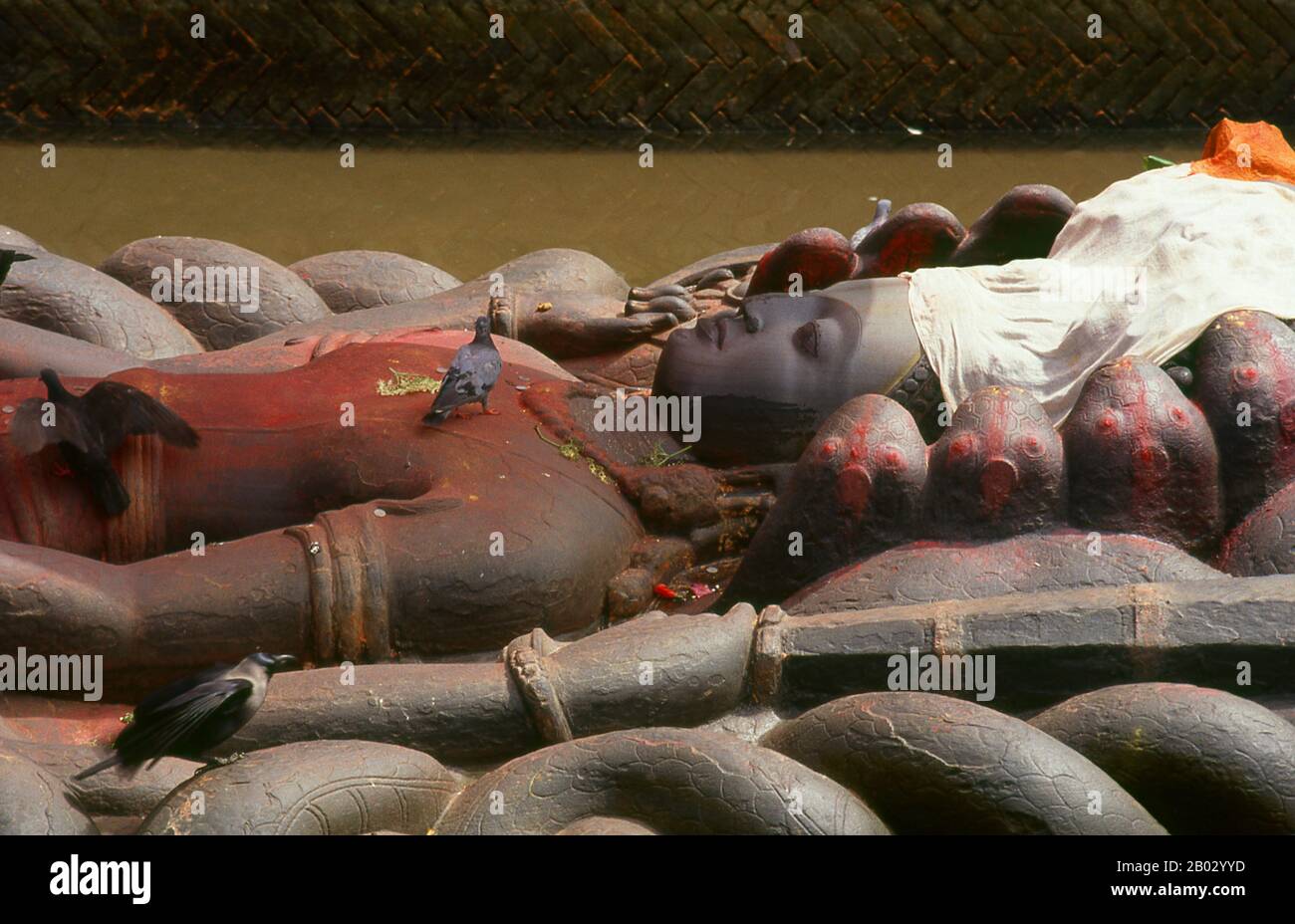 Die Vishnu-Figur der Budhanilkantha ist eine 4,5 Meter lange, aufwändig geschnitzte Figur, die Vishnu schlafend auf dem Boden des kosmischen Ozeans darstellt, auf einem "Bett" aus ineinander verschlängelten Schlangenkörpern, die alle Teil der elfköpfigen Riesenschlange Ananta sind, "Die Endlose". Die Figur stammt vermutlich aus dem 7. Jahrhundert und ist aus einem einzigen Stück Felsen gehauen. Der Legende nach wurde Budhanilkantha von einem Bauern beim Pflügen seines Feldes entdeckt; der Pflug schnarrte auf der Figur, die unterirdisch verscharrt wurde, und zur großen Überraschung des Bauern begann die Figur zu bluten. Budha bedeutet 'Mud' und Ni Stockfoto