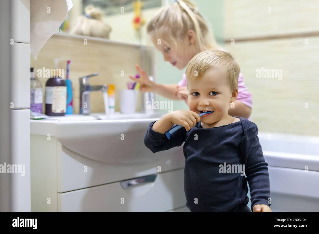 Zwei süße, hübsche blonde, kaukasische Geschwister, die morgens im Bad das  Gesicht waschen und den Zahn mit Zahnbürste reinigen. Kleine Kinder Bruder  und Stockfotografie - Alamy