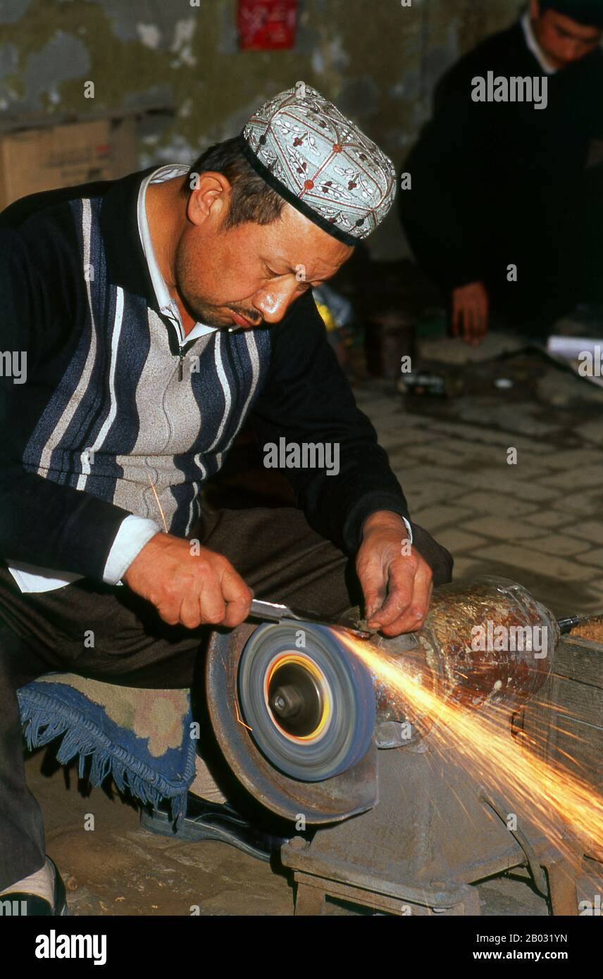 Die kleine von Uiguren dominierte Oase Yengisar (Yingjisha) ist in der gesamten westchinesischen Provinz Xinjiang für die Herstellung von handgefertigten Messern bekannt. Die Kleine Messerfabrik (Pichak Chilik Karakhana/Xiadaochang) beschäftigt erfahrene Handwerker vor Ort, die feine Messer mit eingelegten Griffen herstellen. Fast jeder uigurische Mann trägt ein Messer, sowohl als Zeichen der Manschaft als auch für den utilitareren Zweck, Melonen aufzuschneiden, und die wertvollsten (und teuersten) stammen aus Yengisar. Stockfoto