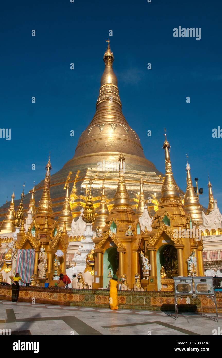 Der goldene Stupa der Shwedagon-Pagode erhebt sich fast 100 m über ihre Lage auf dem Singuttara Hill und ist mit 8.688 Fest-Gold-Platten beschichtet. Dieser zentrale Stupa ist von mehr als 100 weiteren Gebäuden umgeben, darunter kleinere Stupas und Pavillons. Die Pagode war bereits gut etabliert, als Bagan Birma im 11. Jahrhundert beherrschte. Königin Shinsawbu, die im 15. Jahrhundert regierte, soll der Pagode ihre heutige Gestalt gegeben haben. Sie baute auch die Terrassen und Wände um den Stupa. Der riesige Stupa hat einen Umfang auf Bahnsteighöhe von 433 m (1.420 ft), mit seiner achteckigen BA Stockfoto