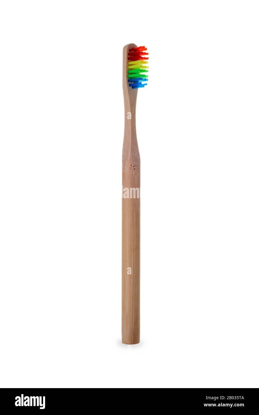 Eine Bambuszahnbürste mit ihren Borsten mit den Farben des Regenbogens auf weißem Hintergrund Stockfoto
