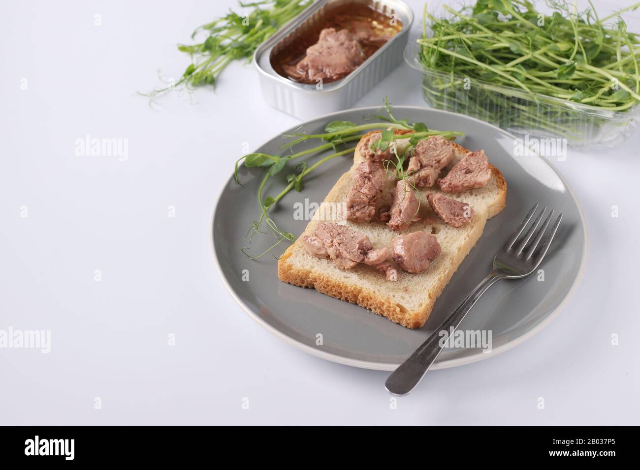 Gesunde Nahrung, Sandwich mit Dorschleber und Erbsen Mikrogrine auf einer  Platte auf weißem Hintergrund Stockfotografie - Alamy