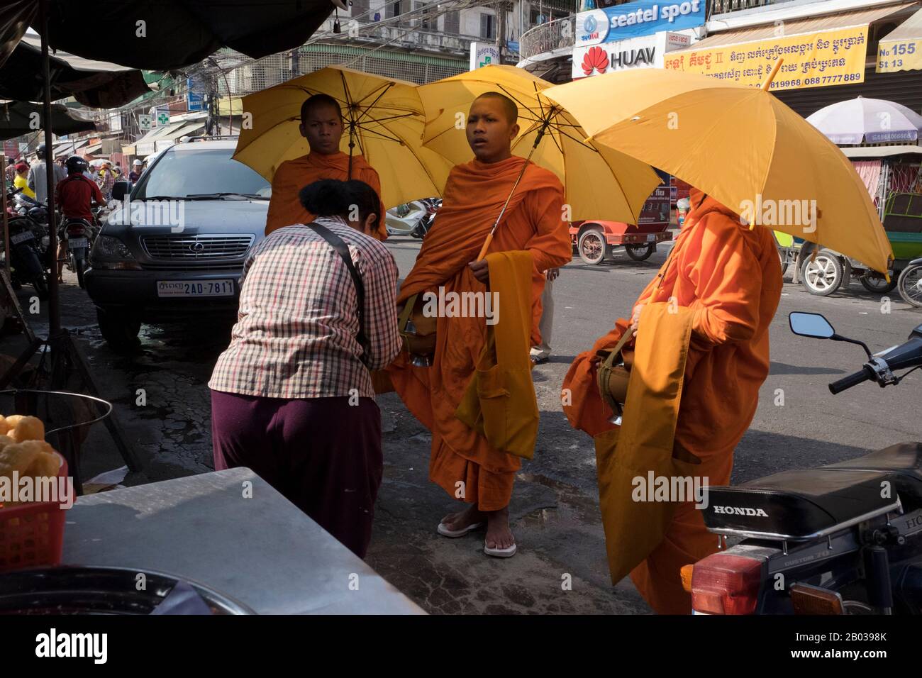 Eine Frau erhält Segen, nachdem sie den Monks Geld auf Almosenrunde auf dem Kandal-Markt, Phnom Penh 2016, angeboten hat. Stockfoto